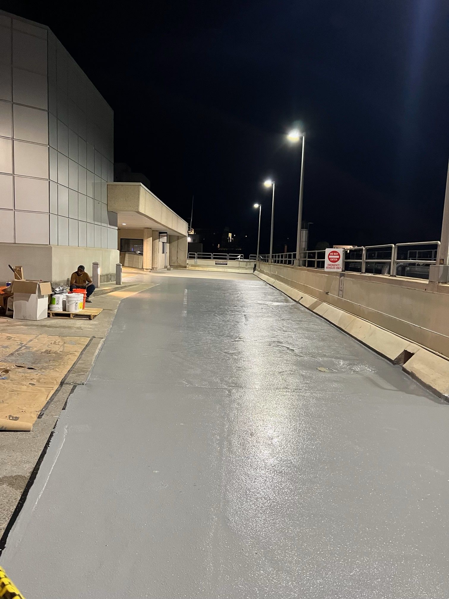 A road with a no parking sign on the side of it at night.