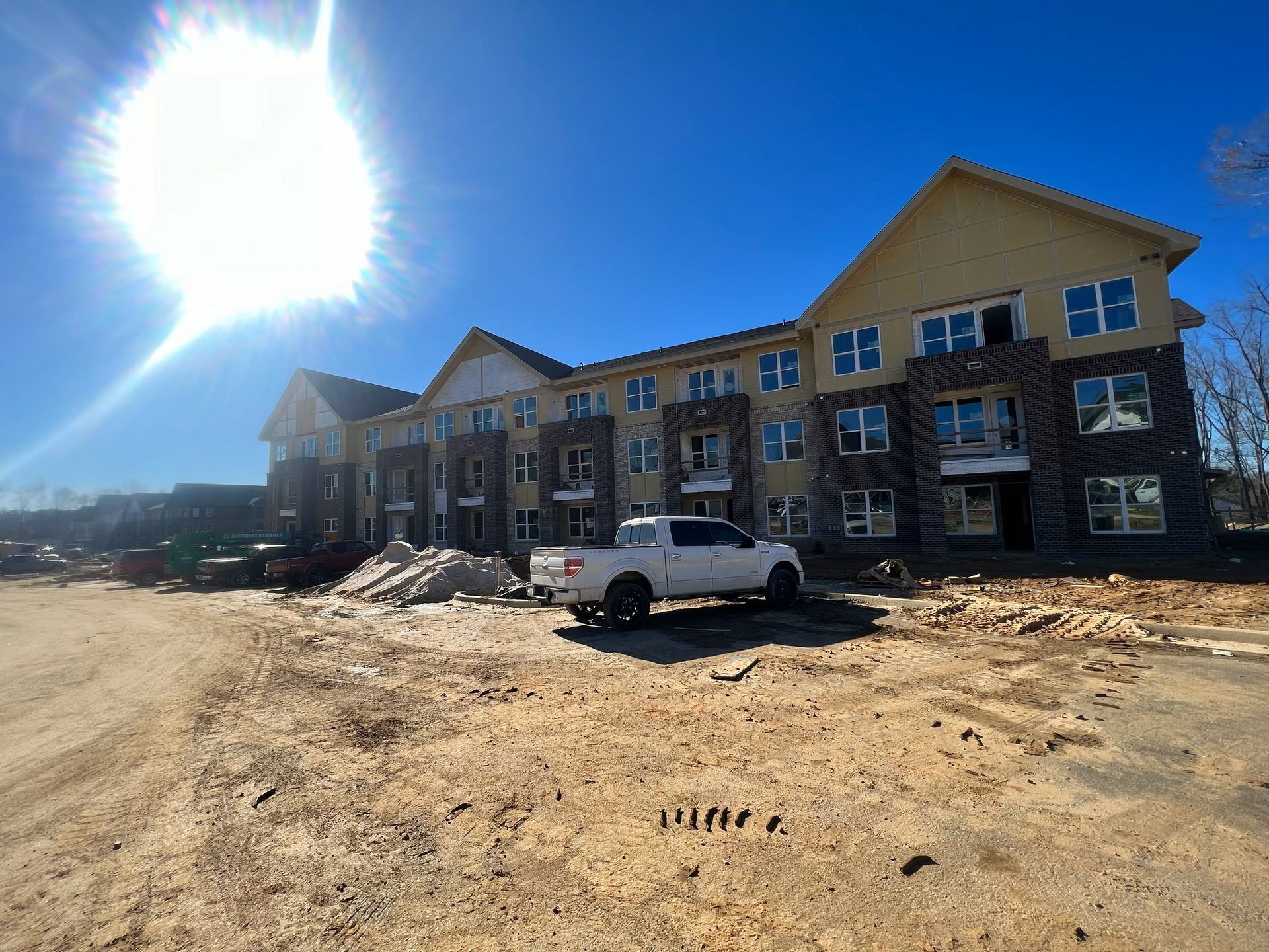A white truck is parked in front of a large building under construction.