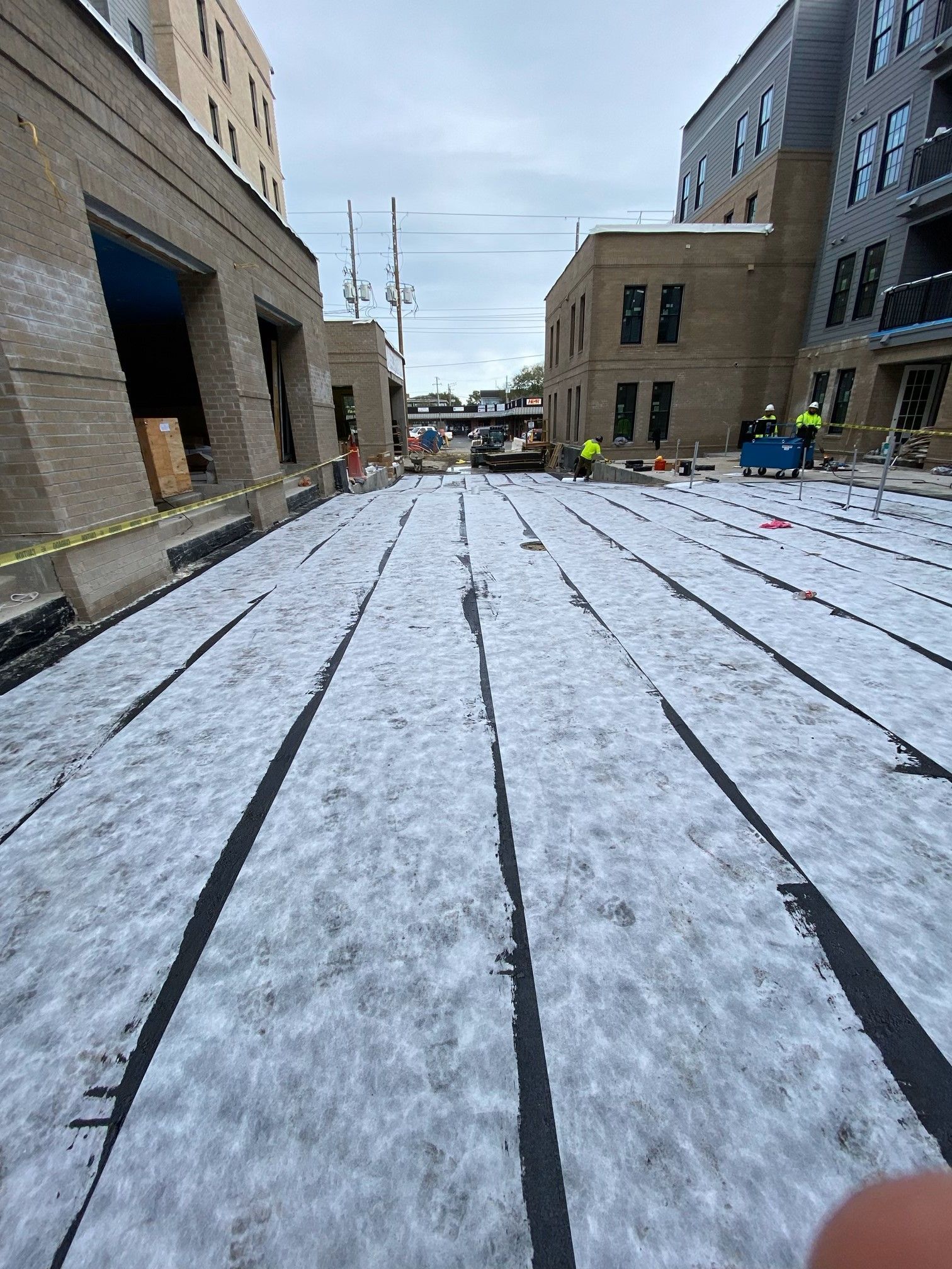 A construction site with a lot of snow on the ground and buildings in the background.