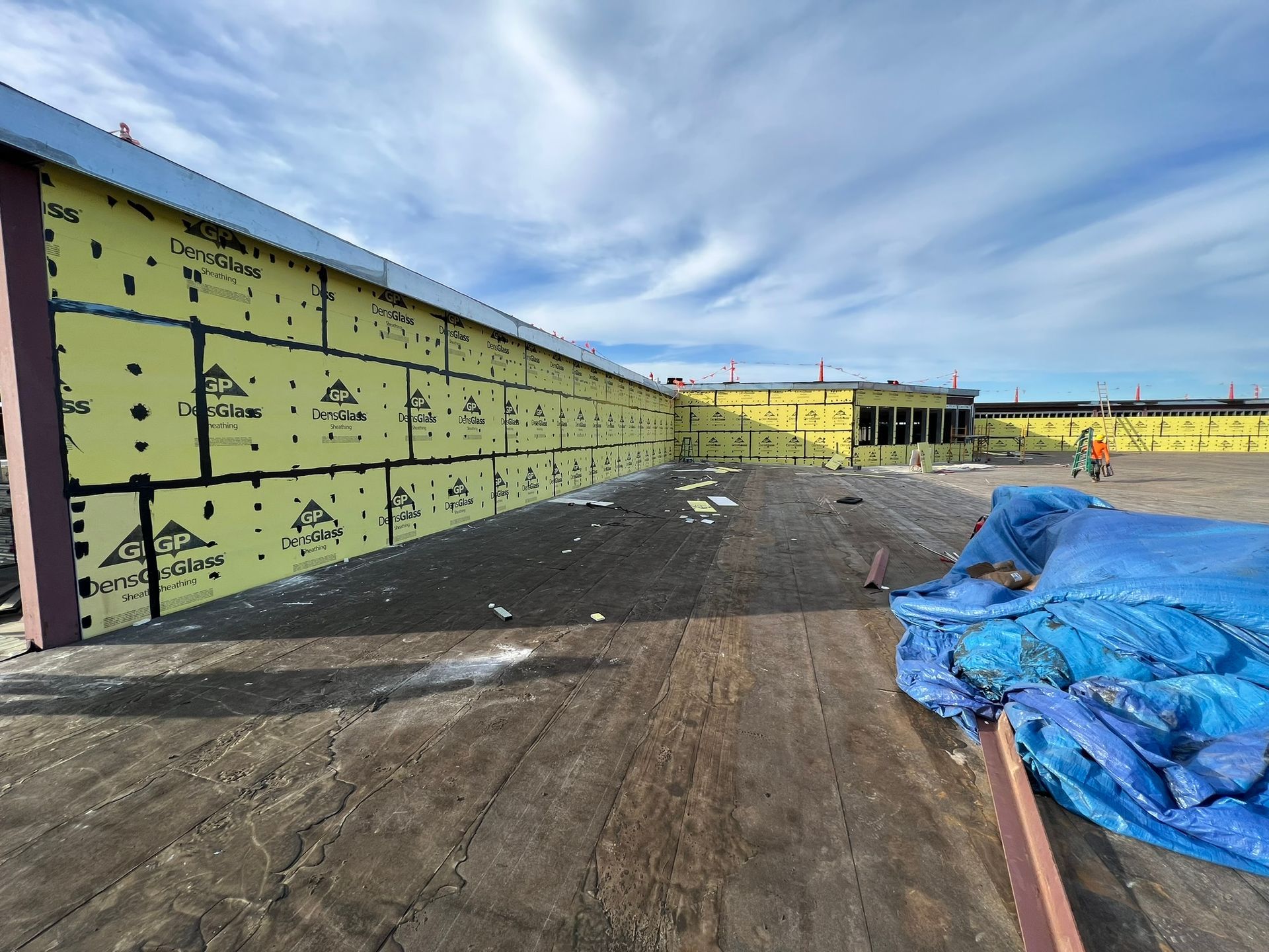 A large building under construction with a blue tarp on the ground in front of it.