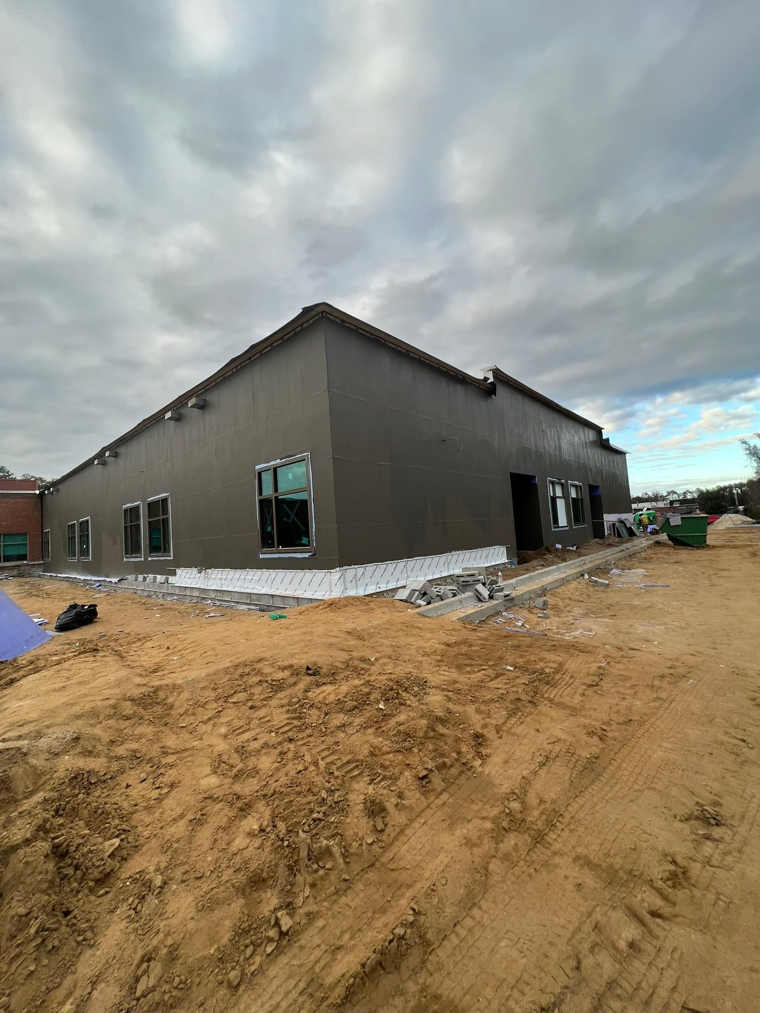 A large building is being built in the middle of a dirt field.