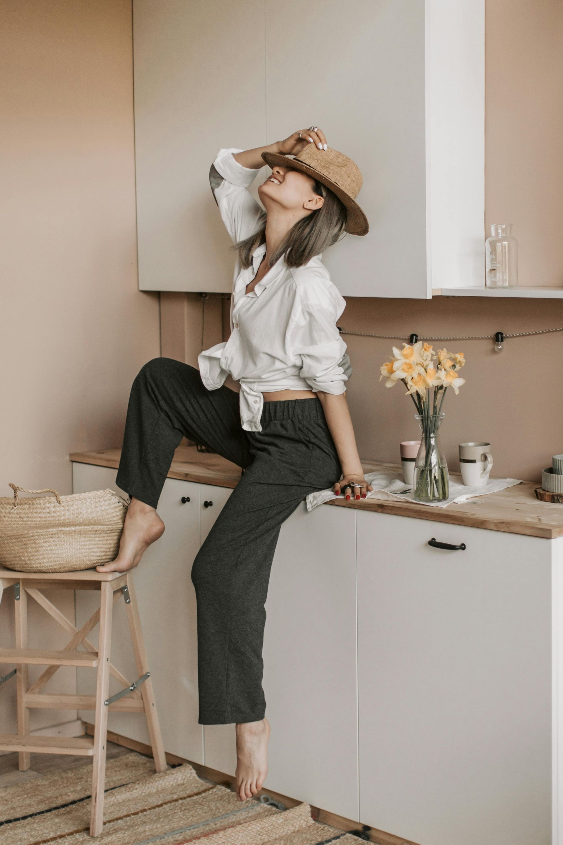A woman is sitting on a stool in a kitchen.