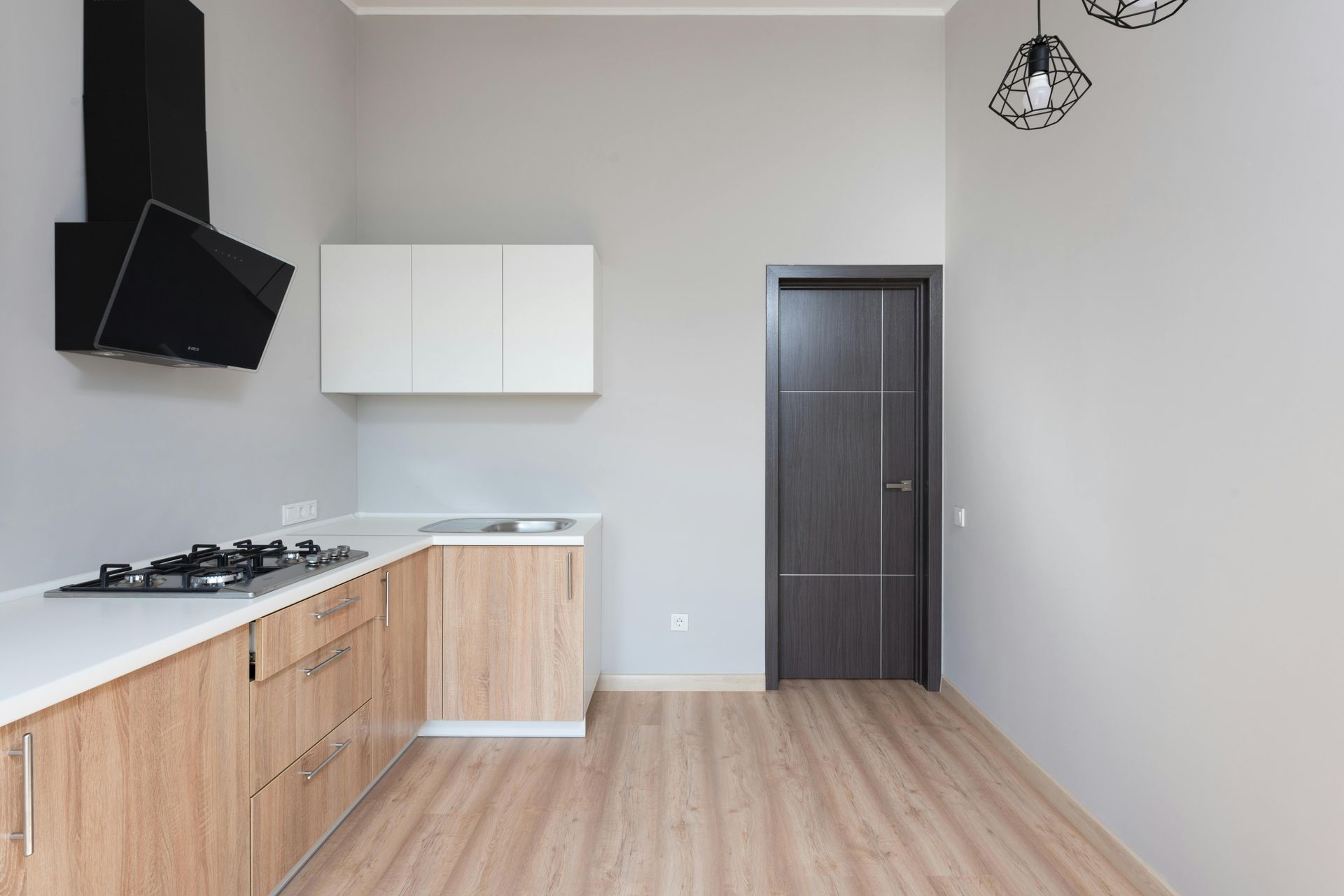 An empty kitchen with wooden cabinets and a stove top oven.