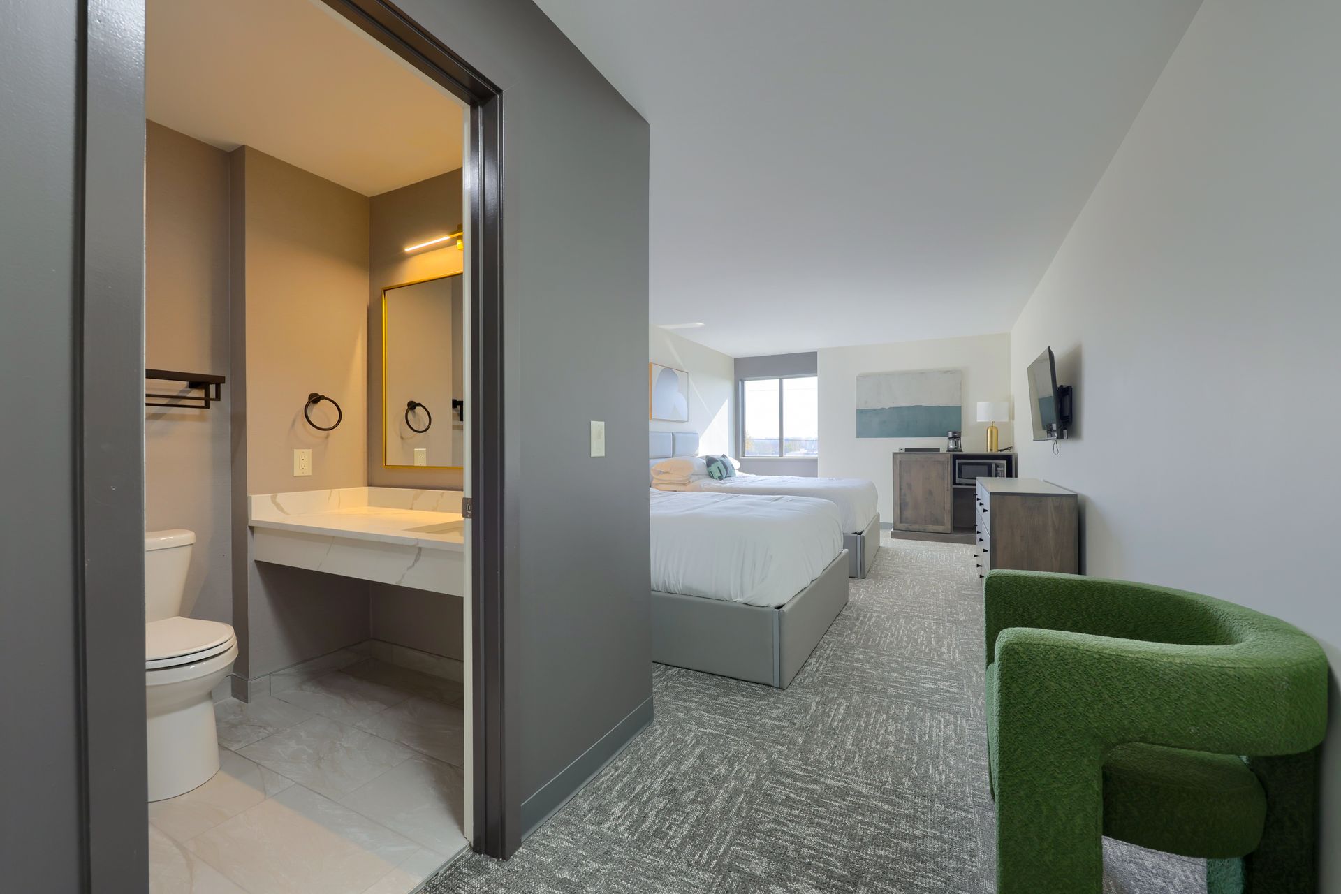 A hotel room with a bed , chair , toilet and bathroom.