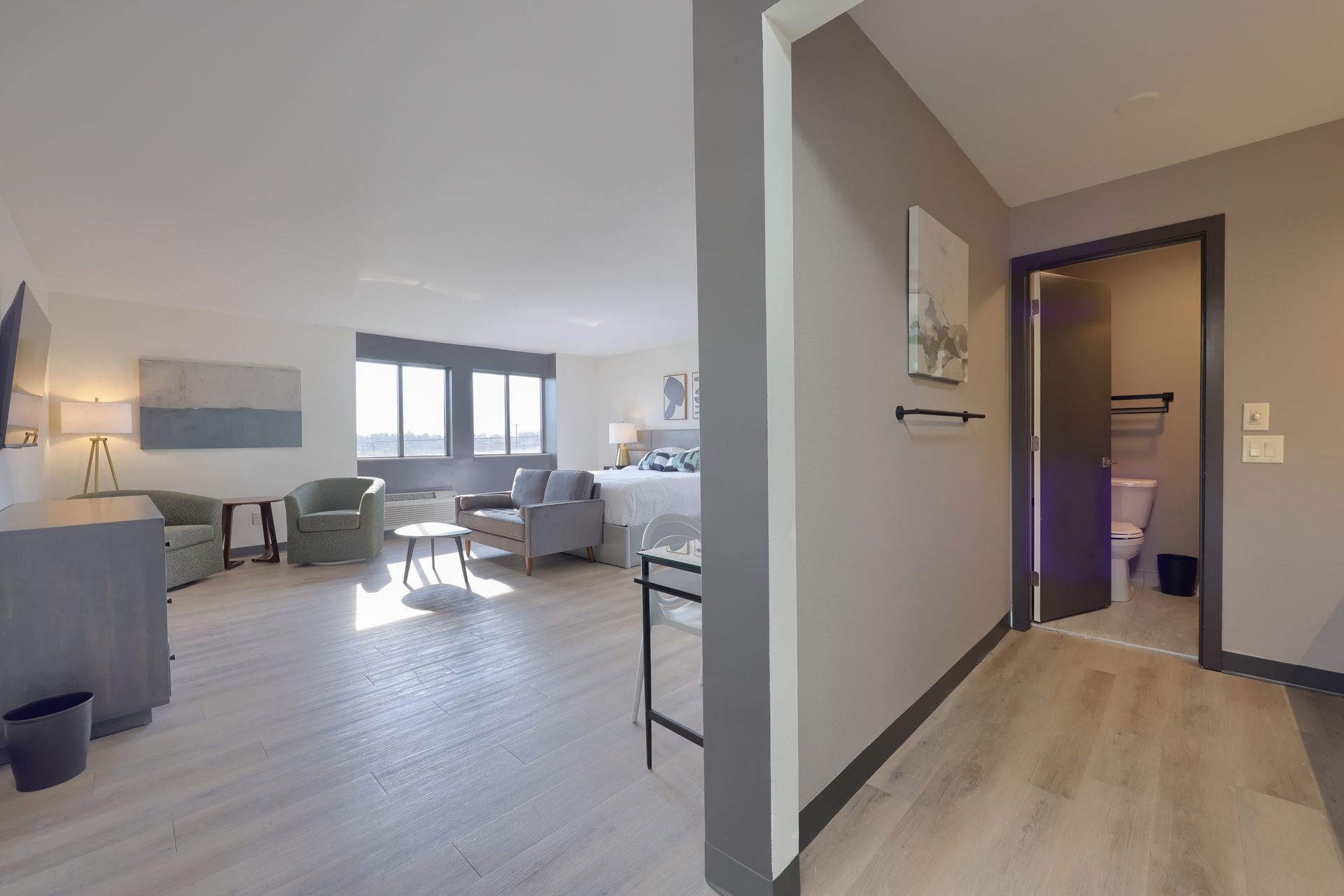 A hotel room with a couch , chairs , and a television