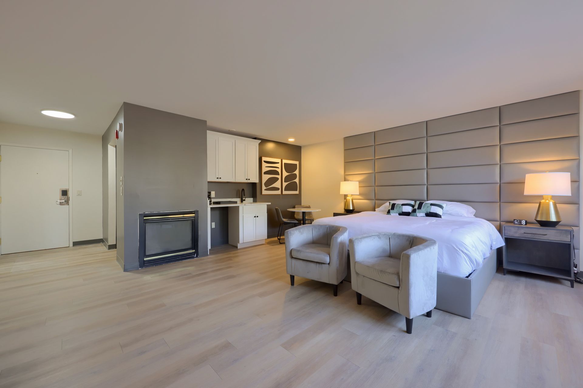 A hotel room with a king size bed and two chairs.