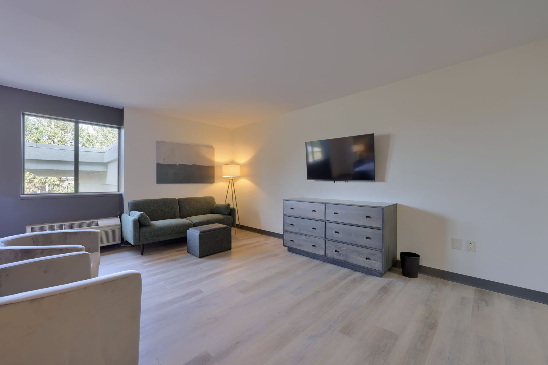 A living room with a couch , chairs , dresser and television.