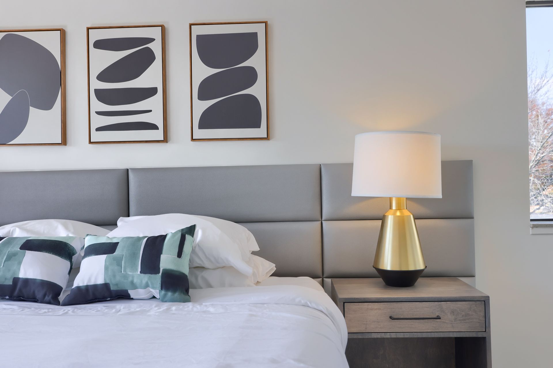 A bedroom with a bed a nightstand and a lamp