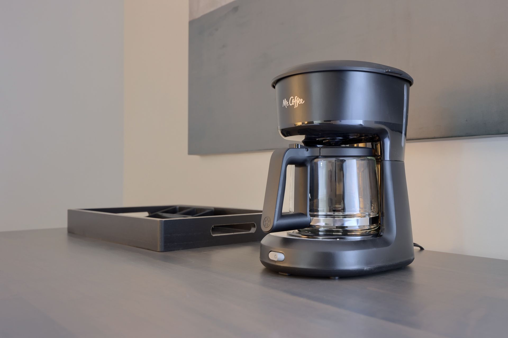 A coffee maker is sitting on a counter next to a tray.