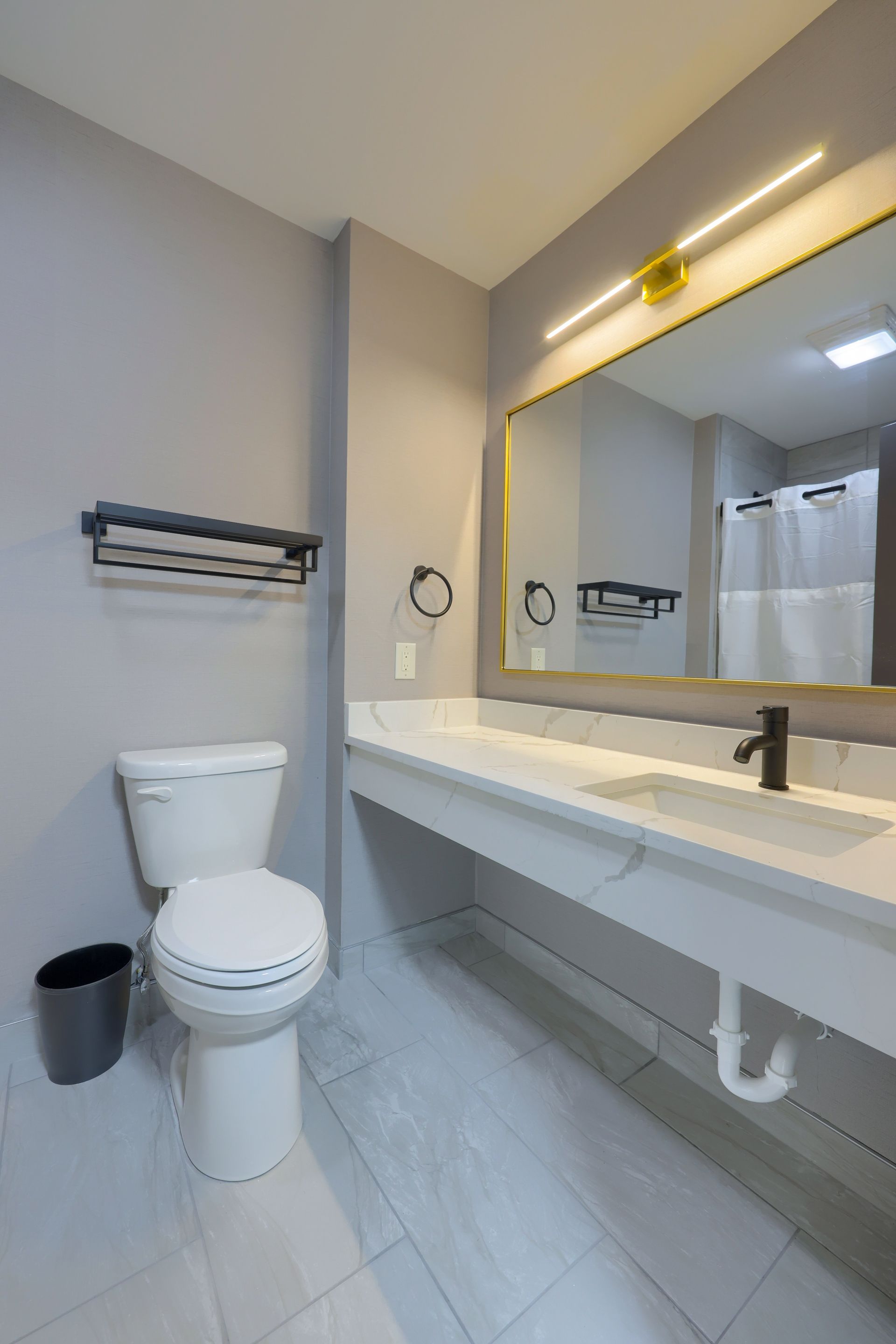 A bathroom with a toilet , sink and mirror.