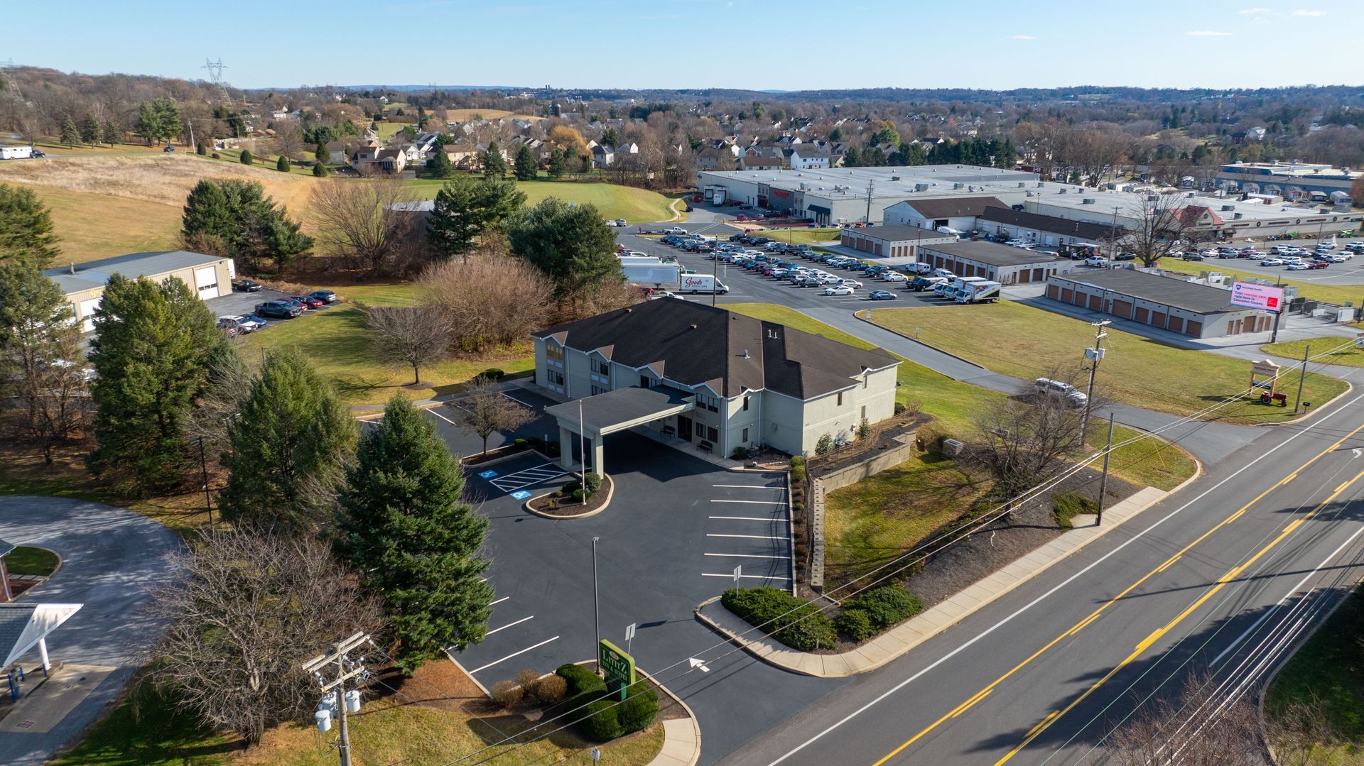 An aerial view of a hotel and a parking lot next to a road.