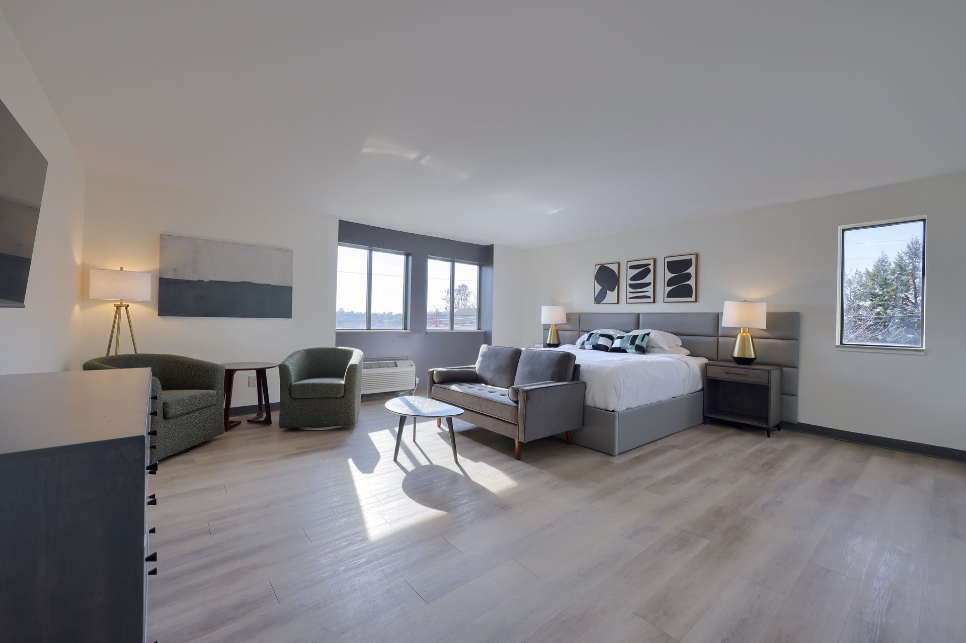 A hotel room with a king size bed , couch , chairs and a television.