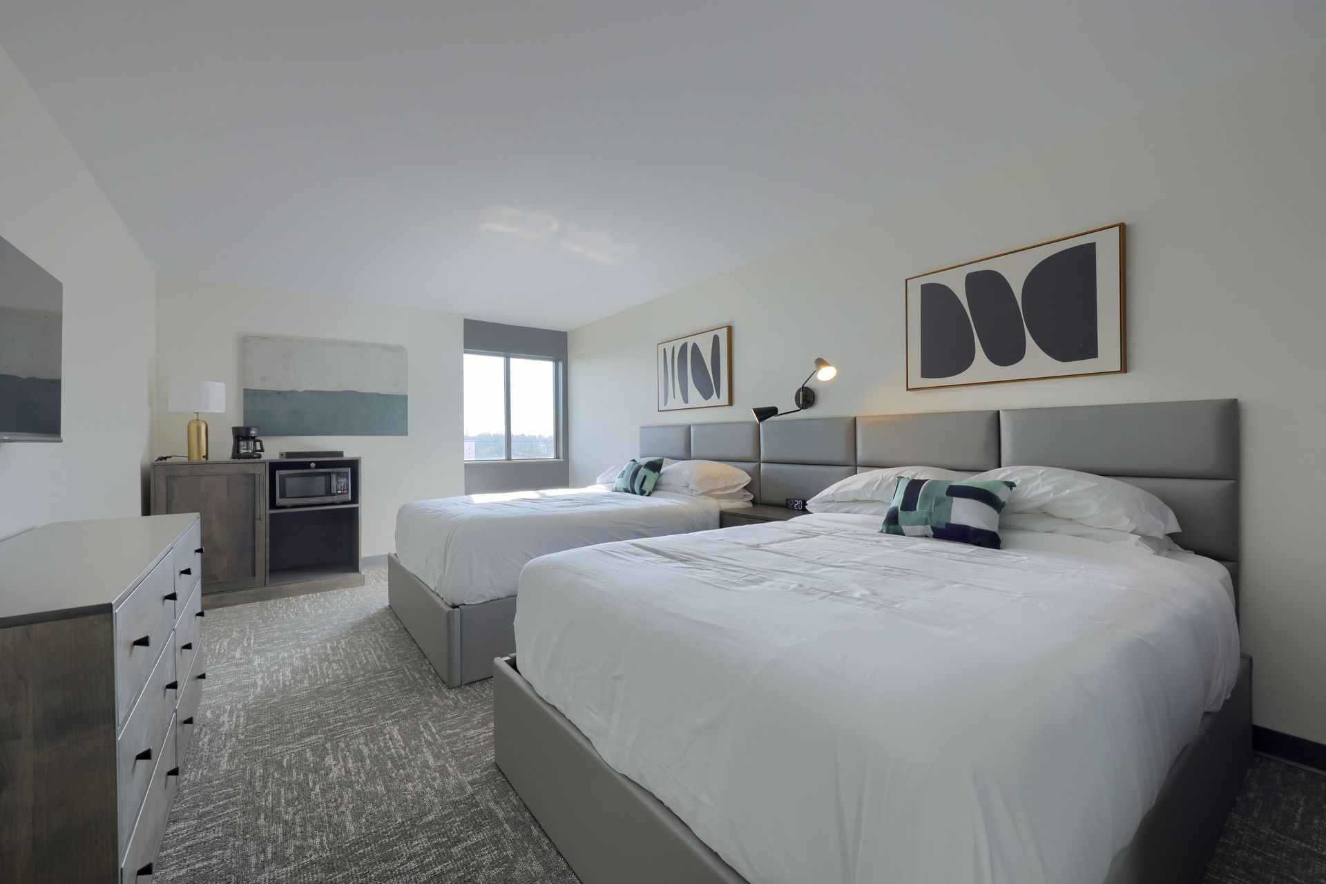 A hotel room with two beds and a dresser.