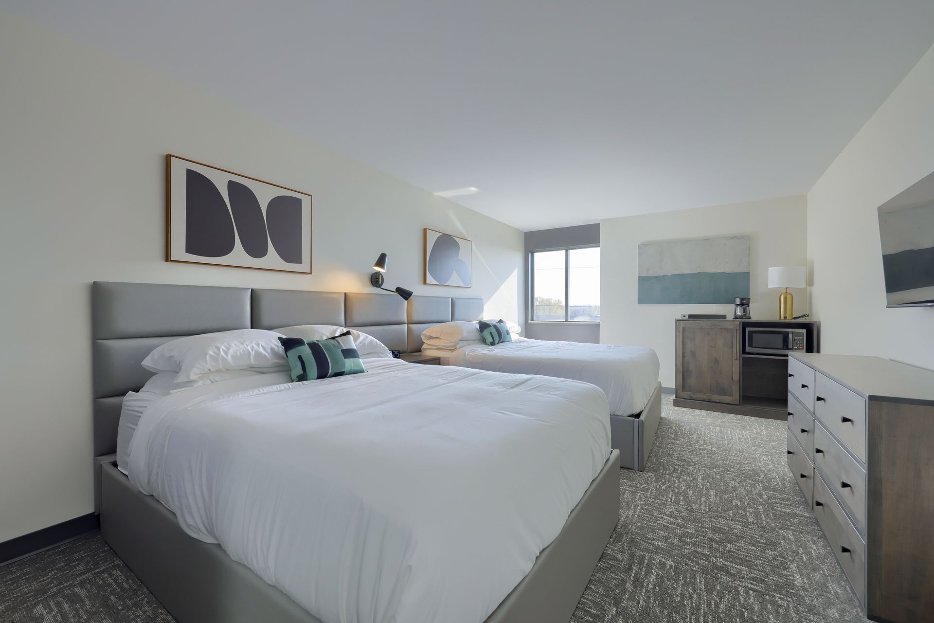 A hotel room with two beds and a dresser.