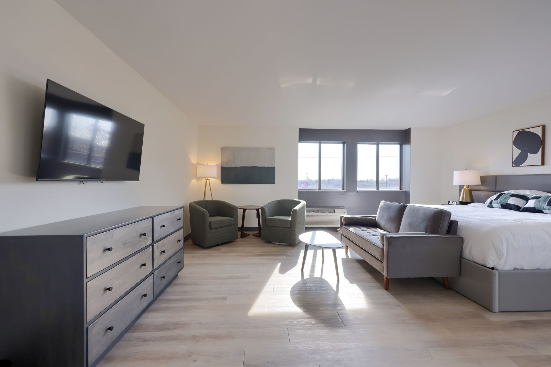 A hotel room with a king size bed , couch , chairs and a flat screen tv.