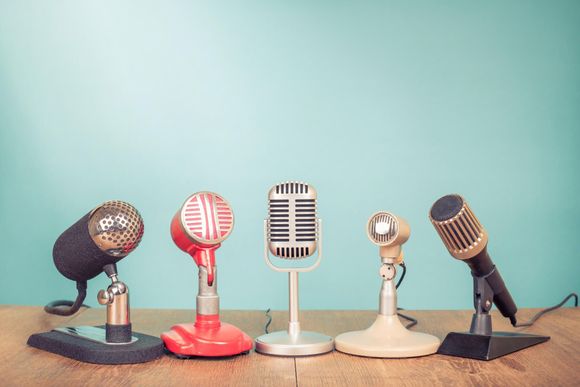 A group of microphones sitting on top of a wooden table.