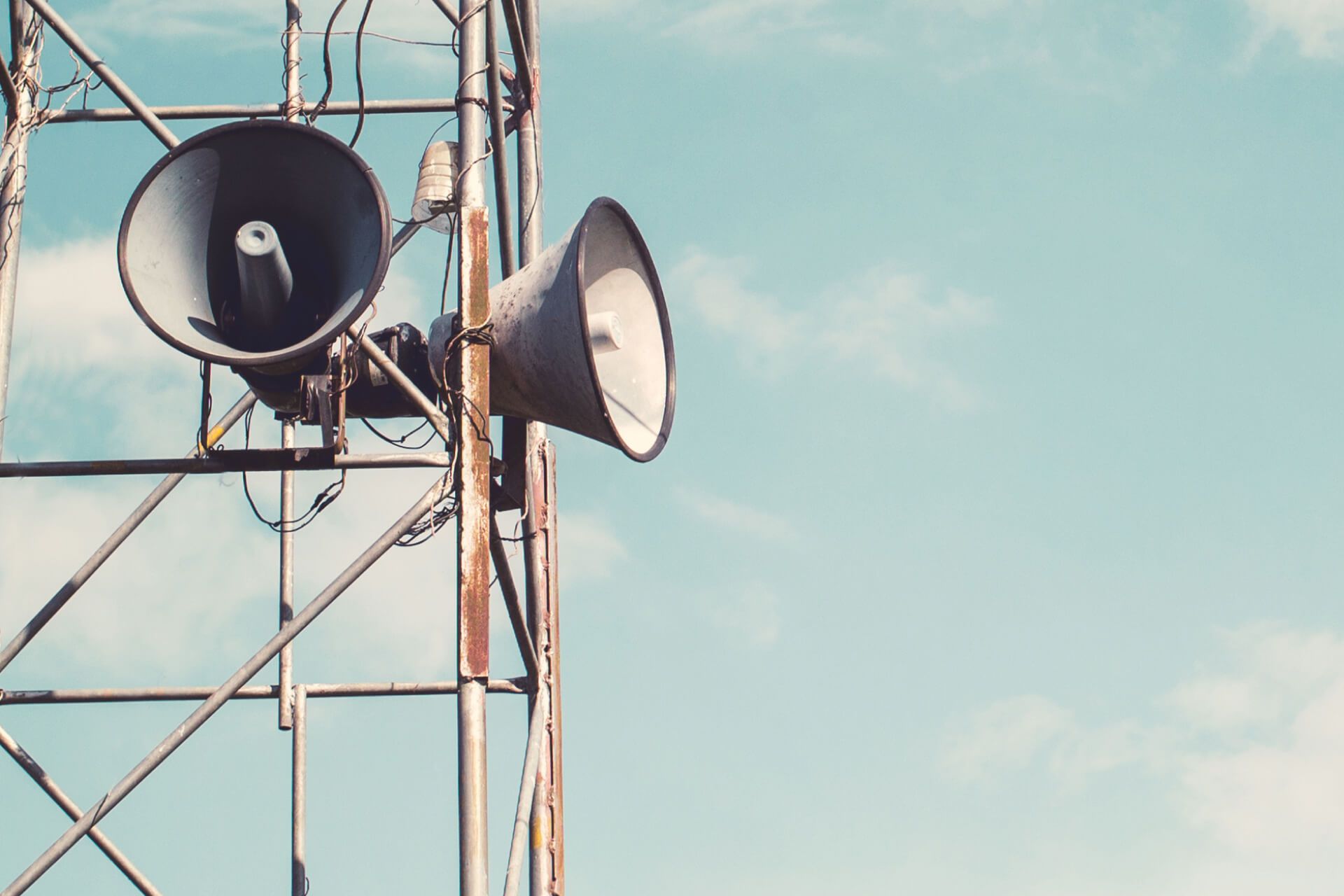 A tower with two speakers on it against a blue sky.