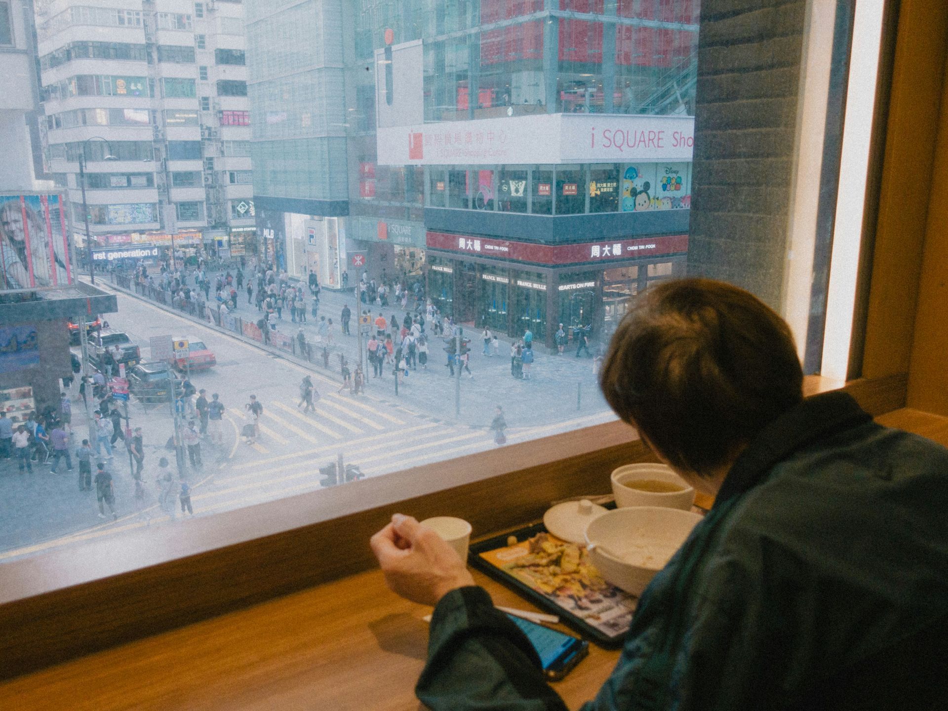 A man looks out of a window overlooking a busy street