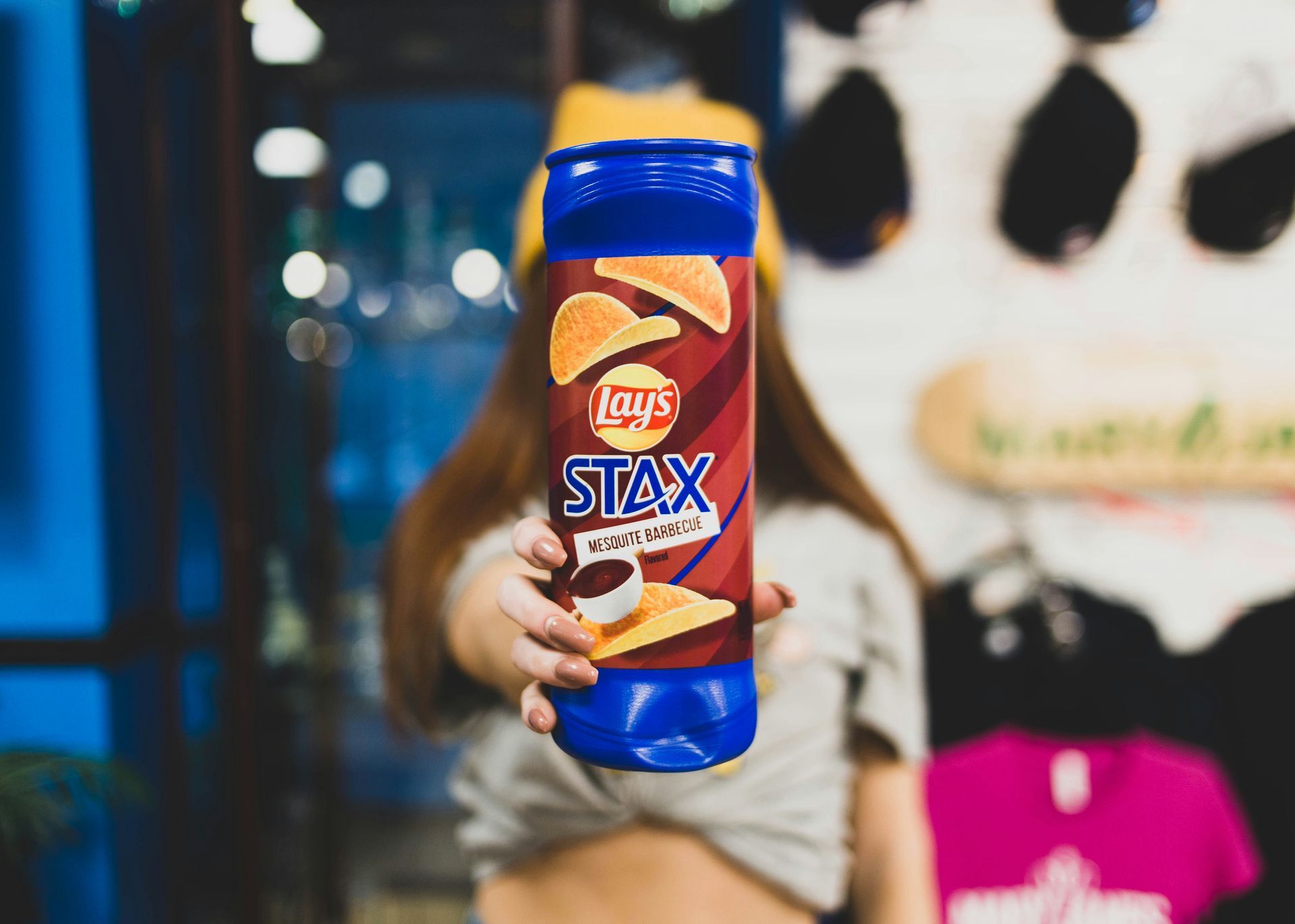 A woman holds a tube of Lay's Stax crisps in the foreground of the photo