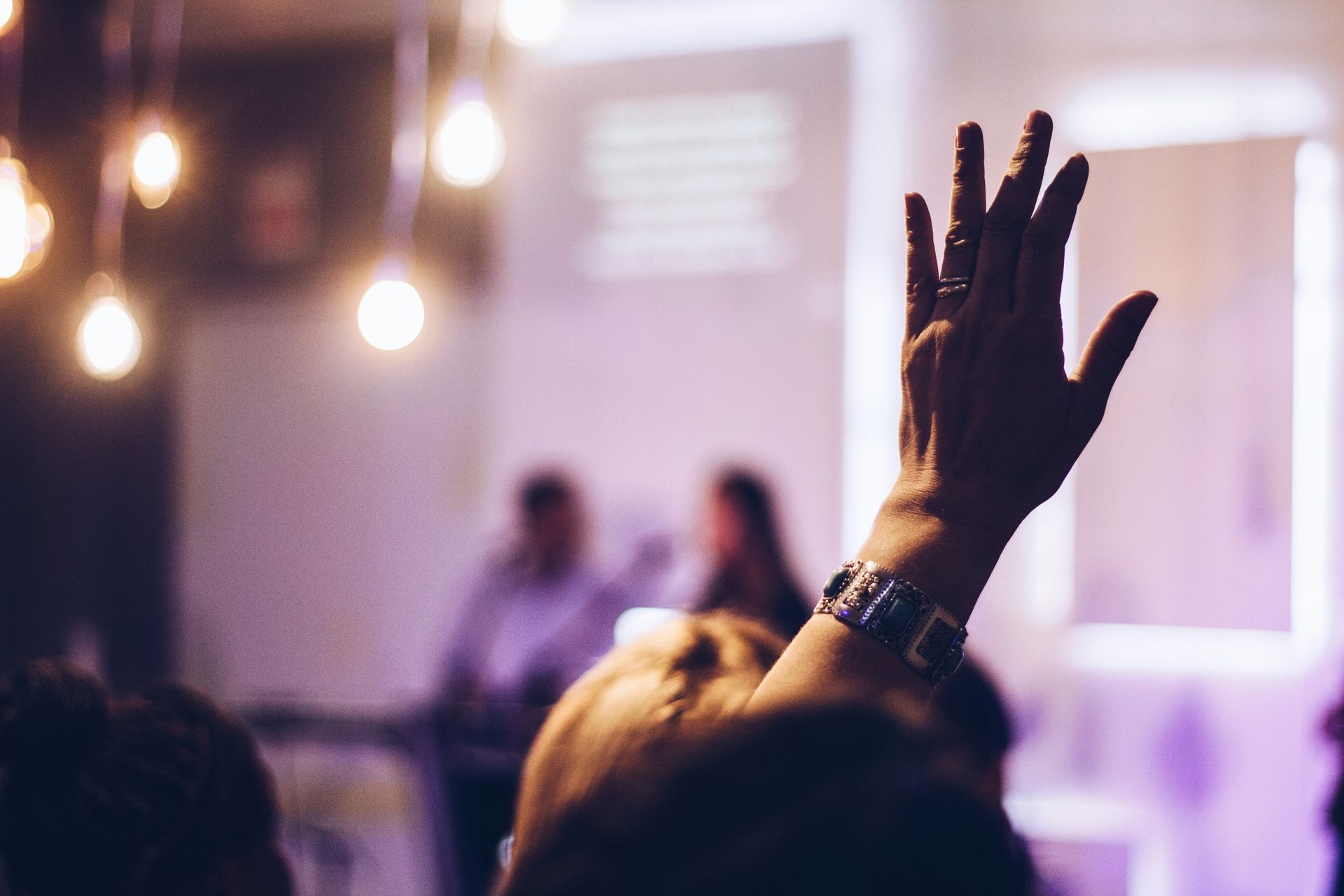 Close up of a raised hand in the audience