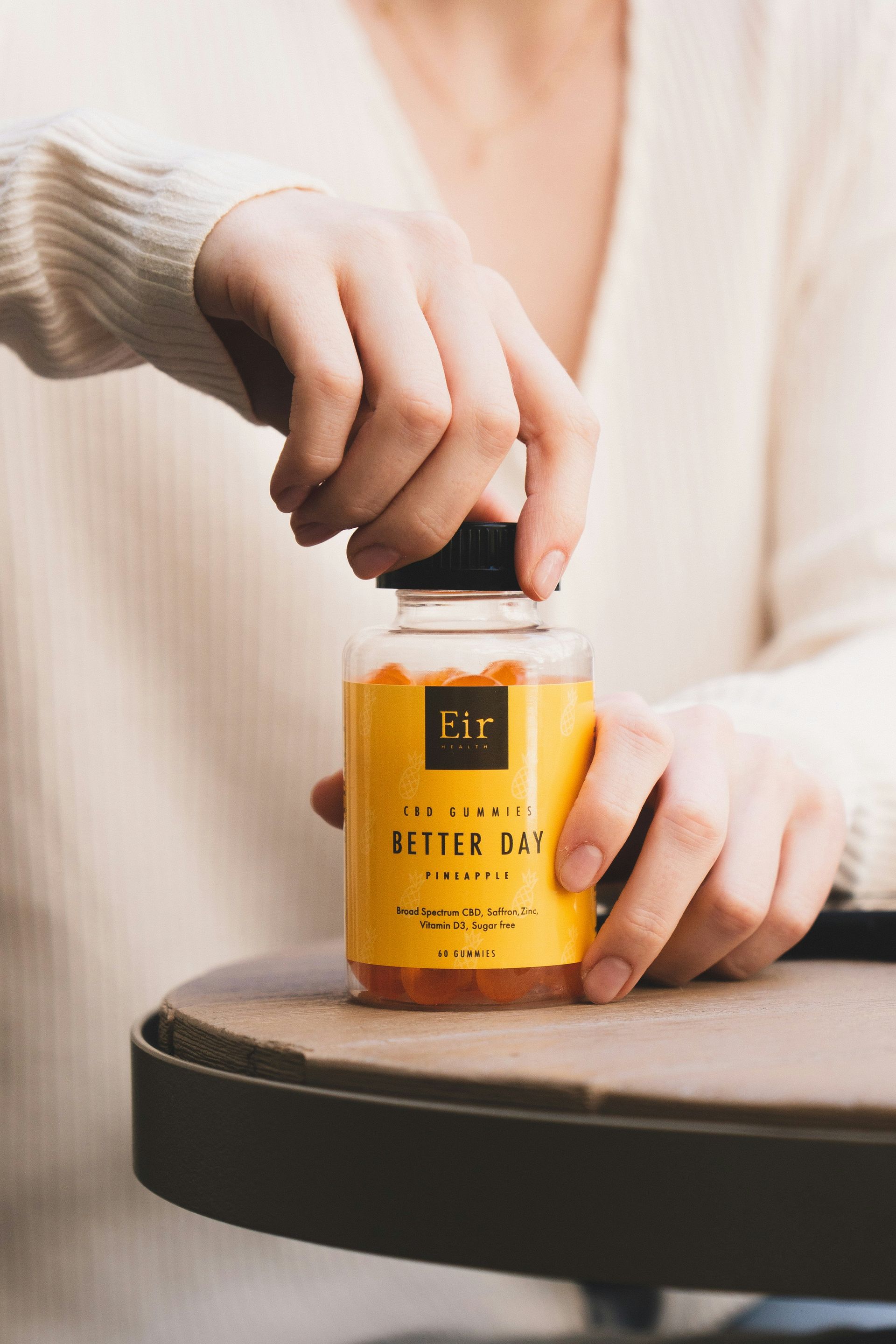 A woman opens a jar of supplements with the label 'Better Day'