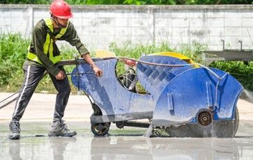 A man is cutting concrete with a circular saw.