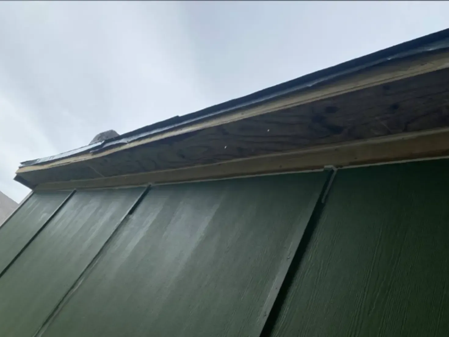 Green panels below a roof's edge, showing a dark, overcast sky.