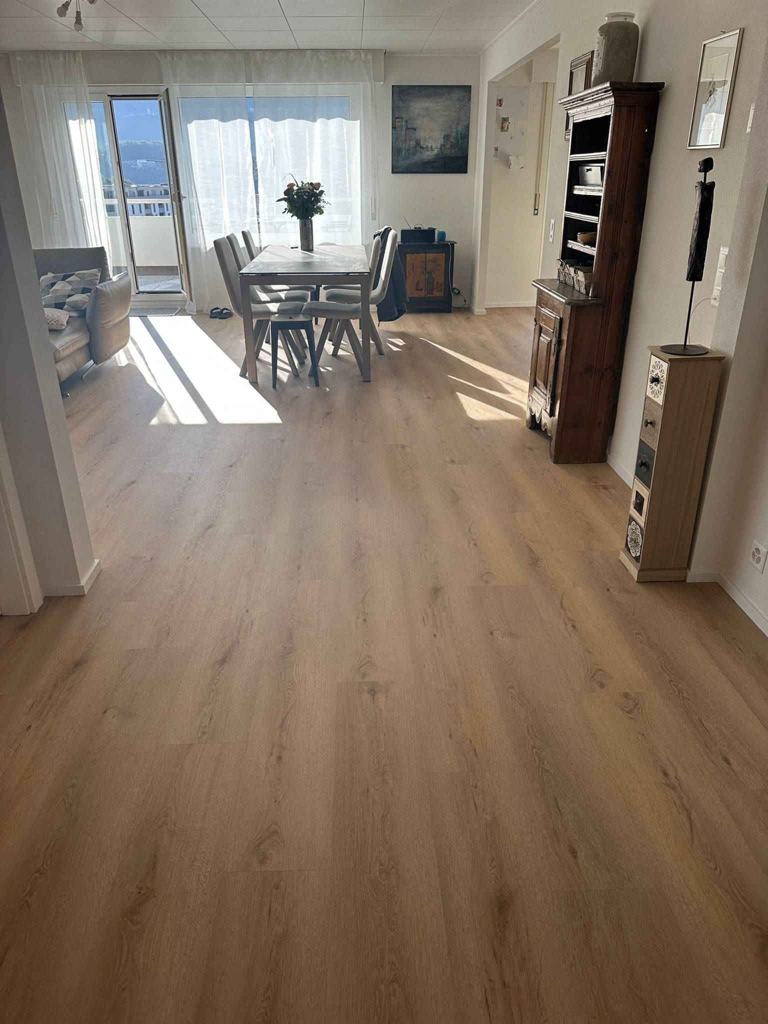 Un salon avec un parquet au sol et une table et des chaises de salle à manger.