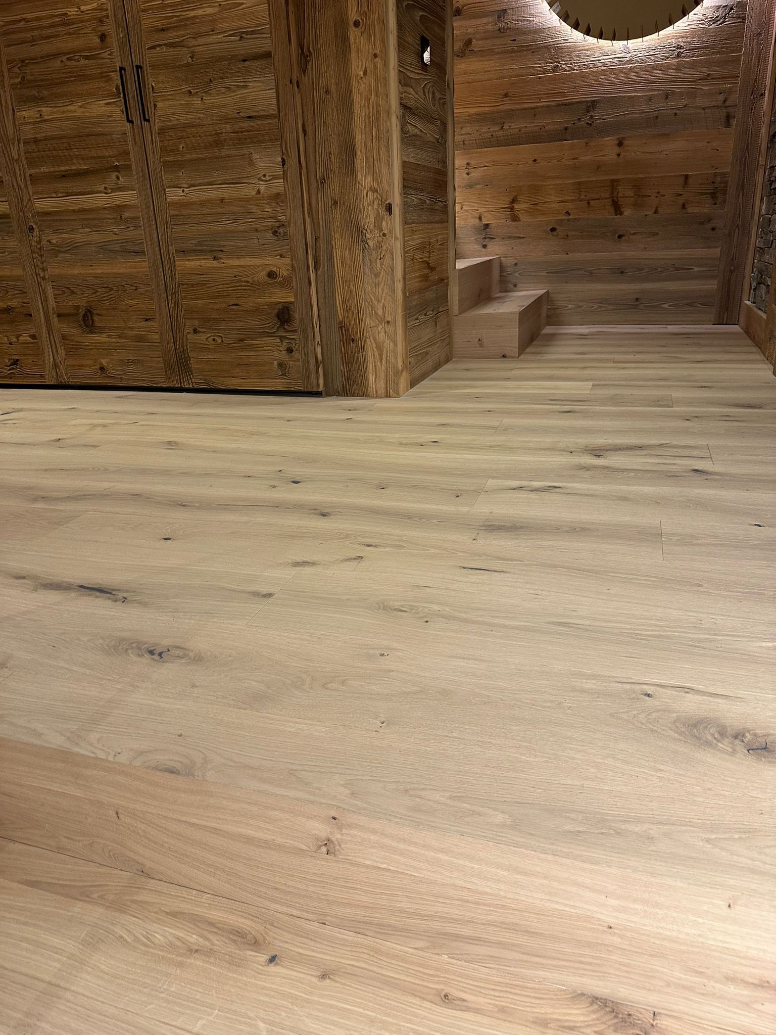 Un plancher en bois dans une pièce avec un mur et des escaliers en bois.