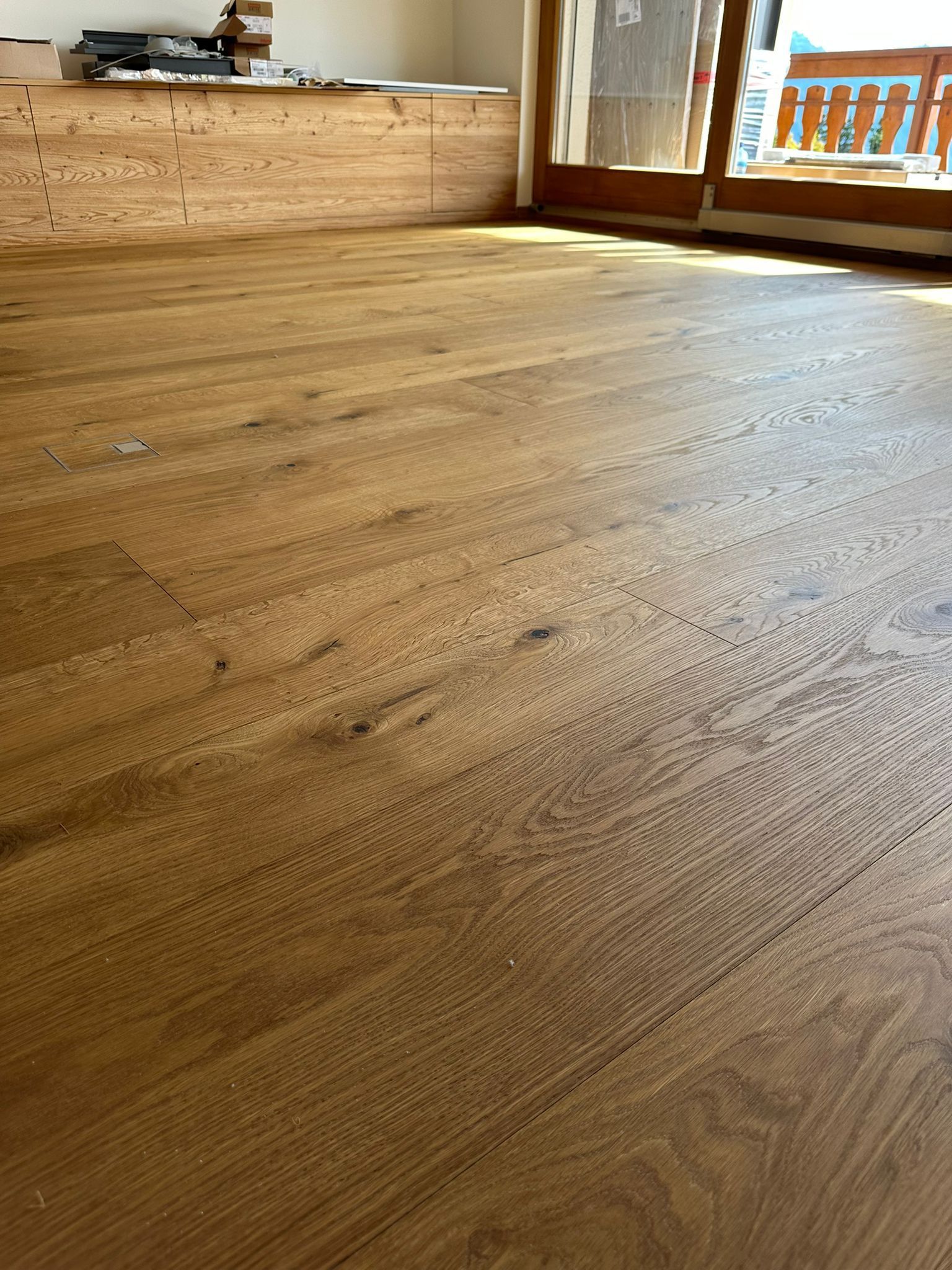 Un plancher en bois dans un salon avec une porte coulissante en verre.