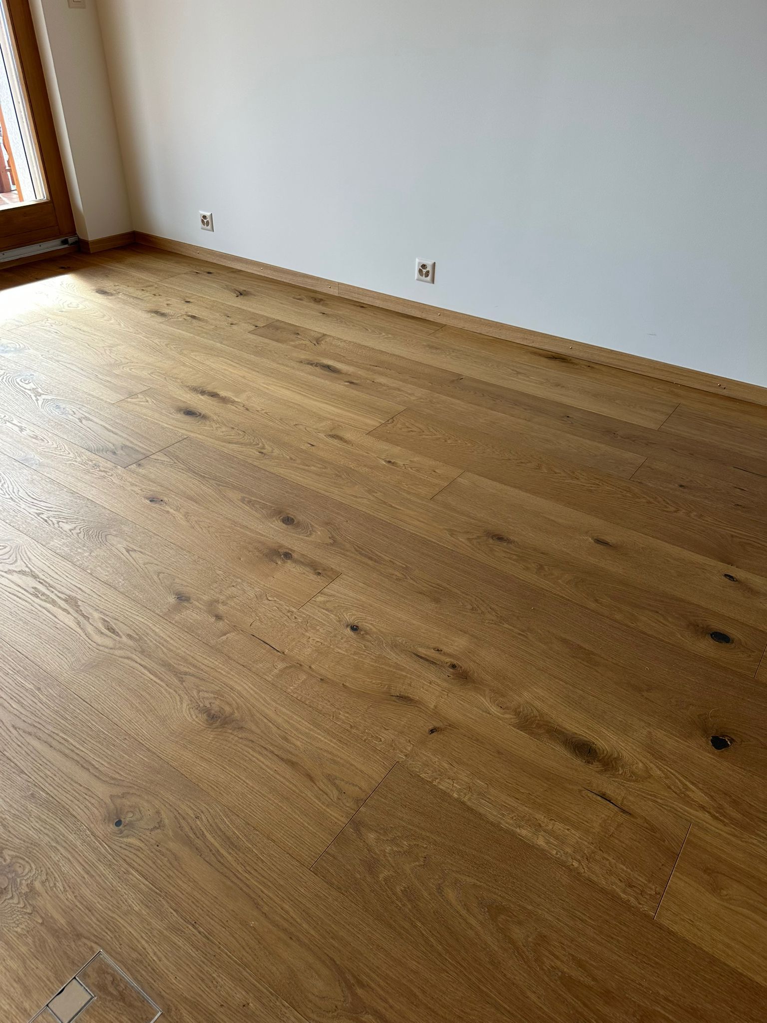 Une pièce avec un plancher en bois et des murs blancs.