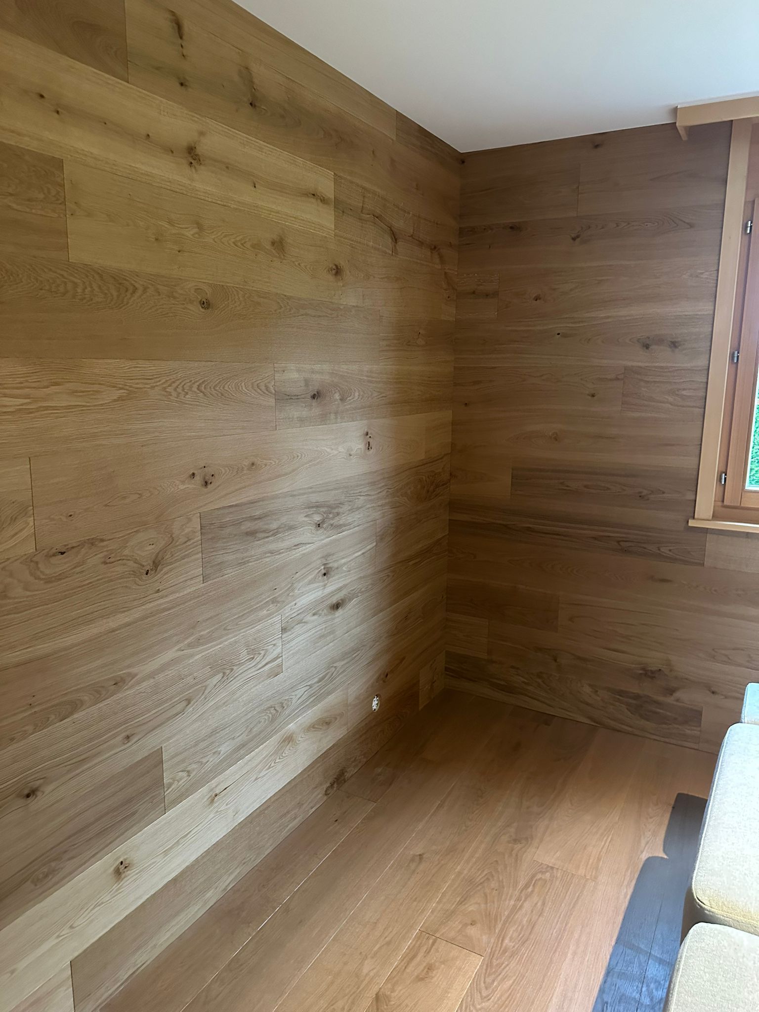 Une pièce avec des murs et du sol en bois et une fenêtre.