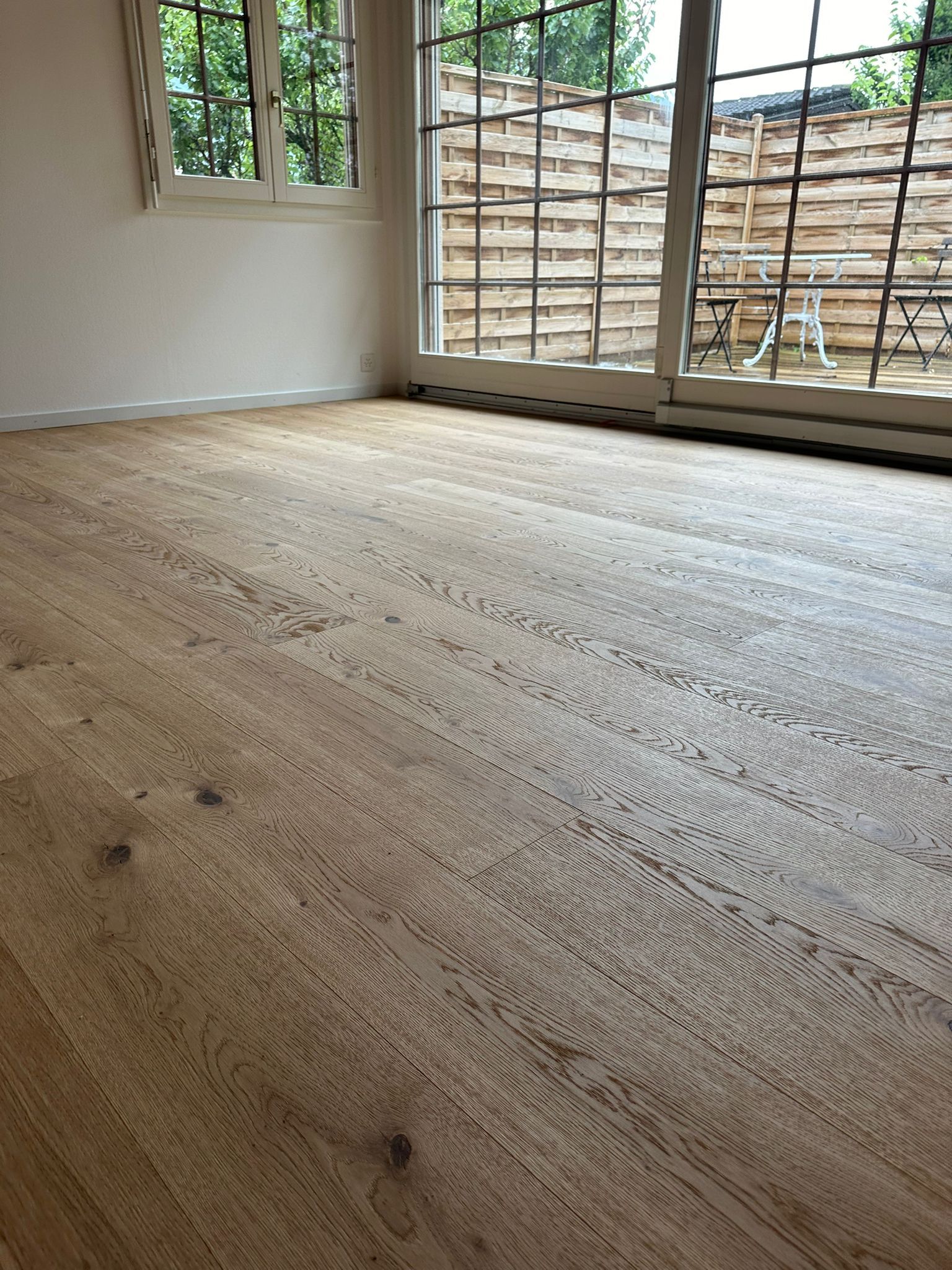 Une pièce avec un plancher en bois et une porte coulissante en verre.