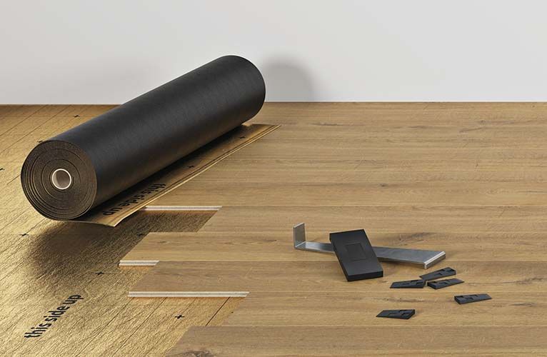 Un rouleau de papier noir est posé sur un plancher en bois.