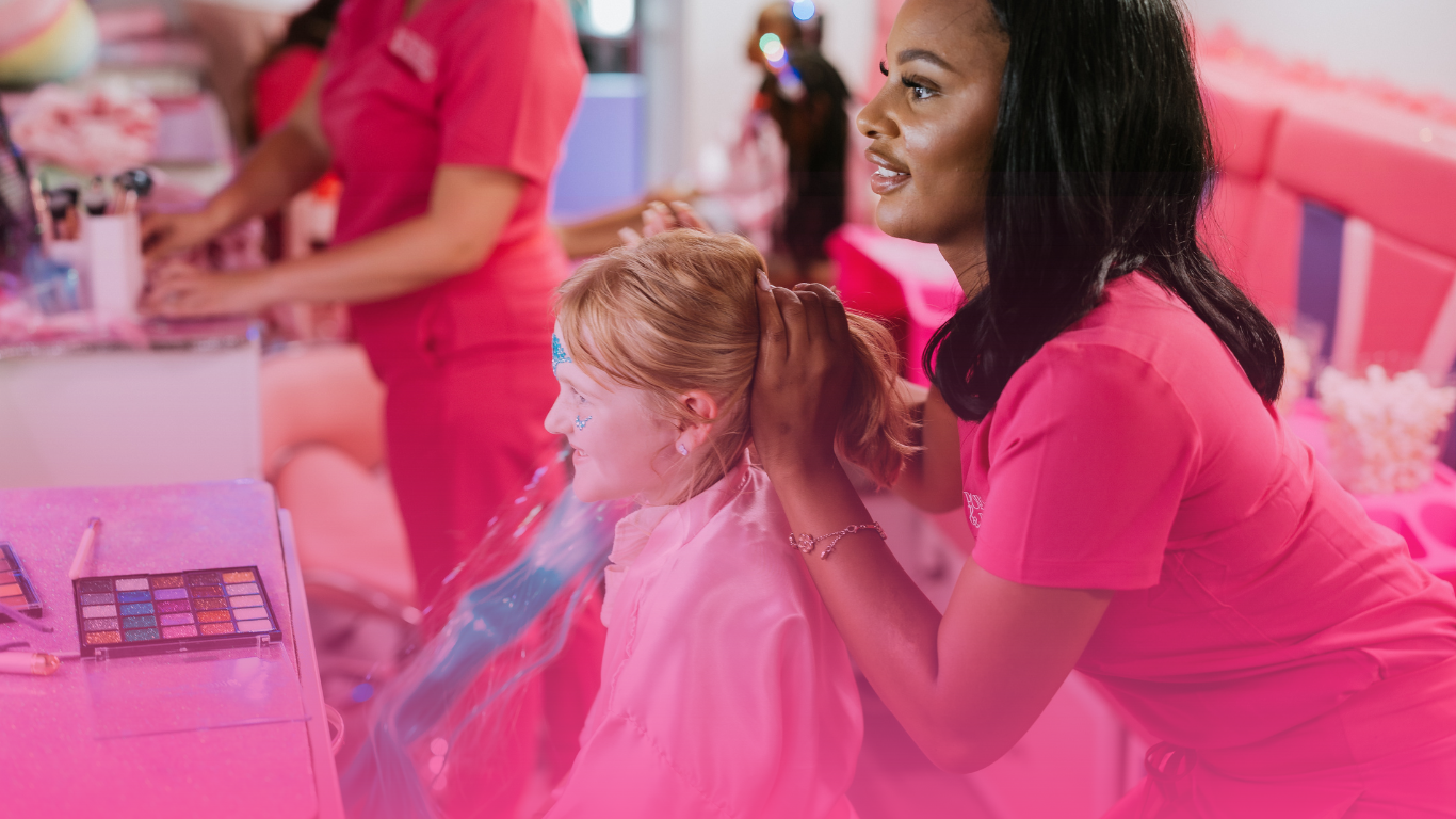 A woman is getting a little girl 's hair done in a pink room.