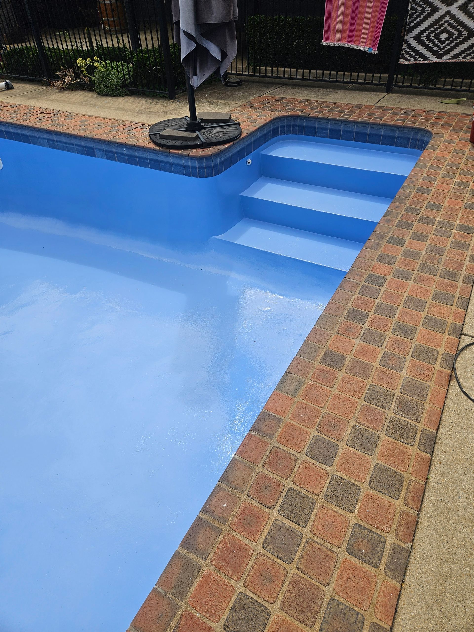 A swimming pool with blue water and steps. Red brick border surrounds it — Riverina Epoxy Flooring In Glenfield Park, NSW