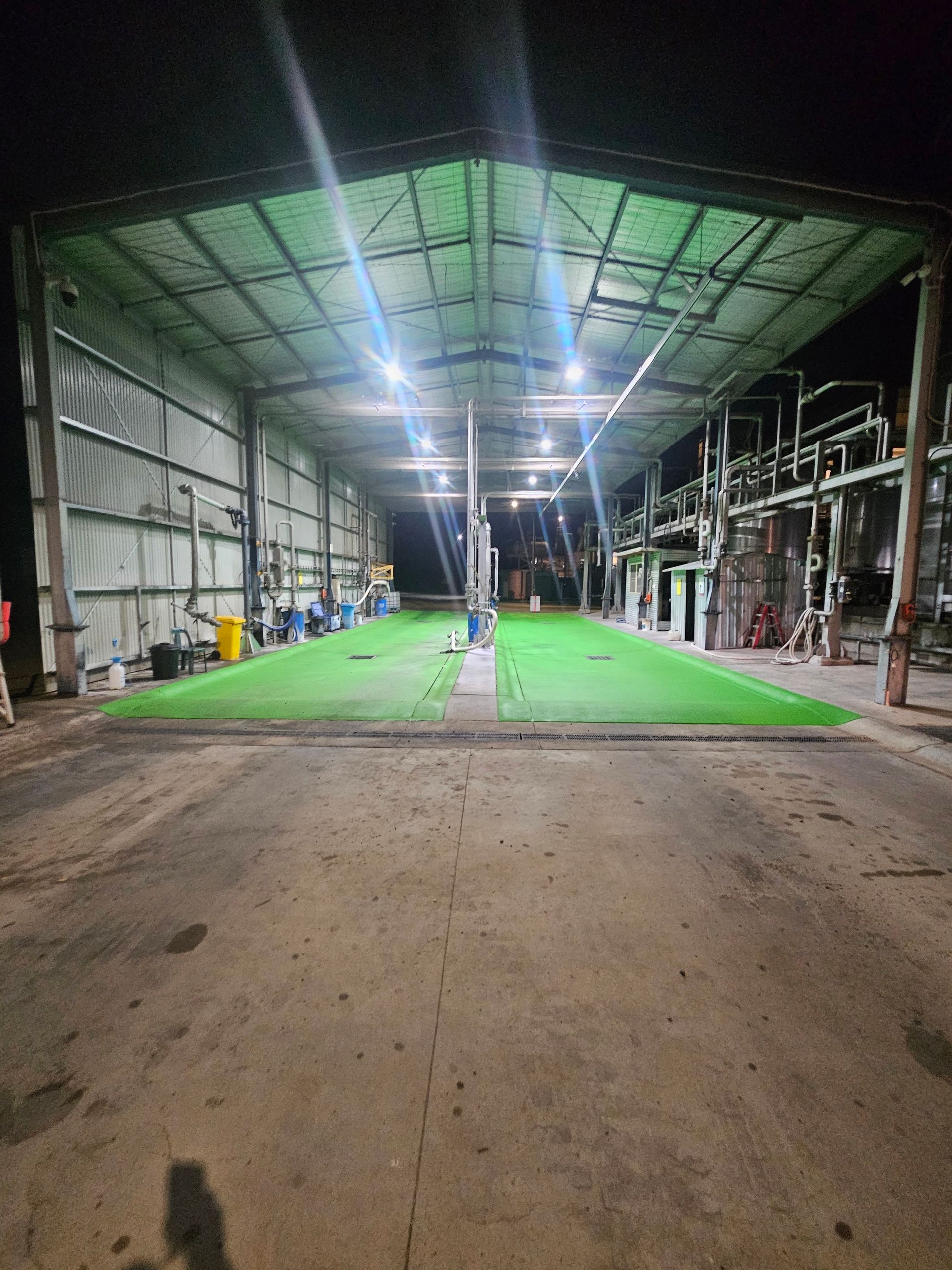 A large industrial shed at night, with green turf and overhead lights — Riverina Epoxy Flooring In Glenfield Park, NSW