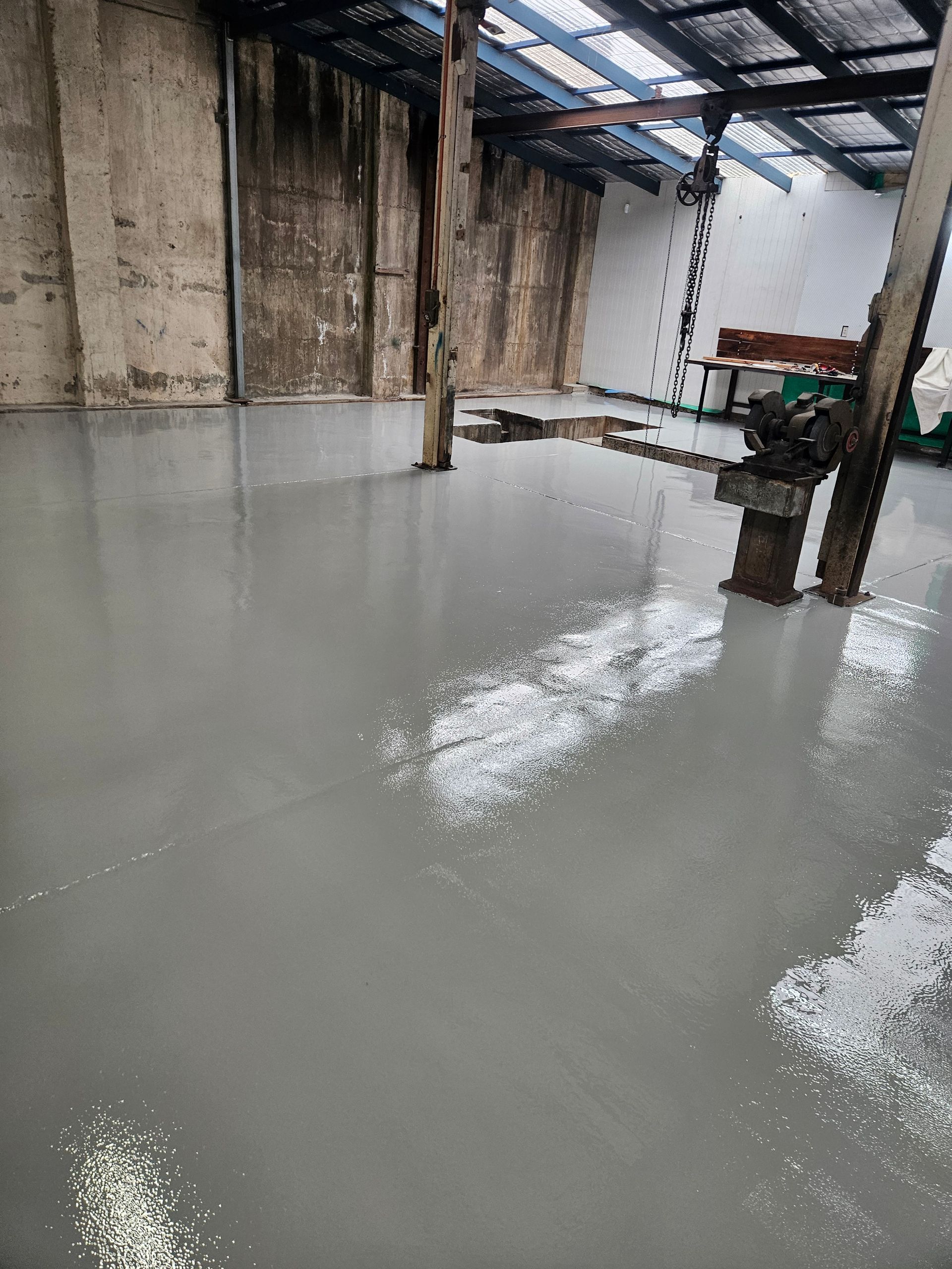 A newly-coated gray concrete floor inside a weathered industrial building — Riverina Epoxy Flooring In Glenfield Park, NSW