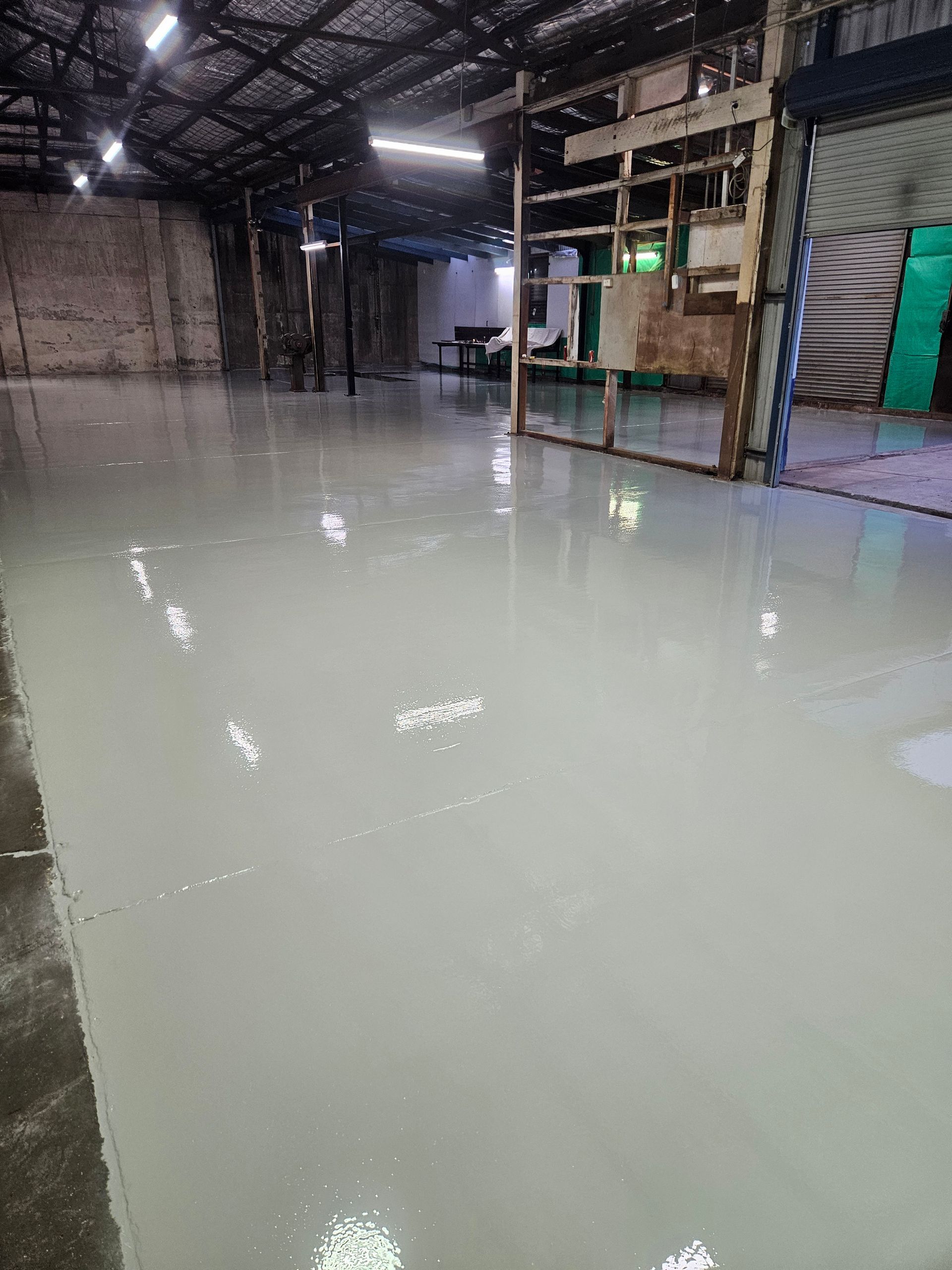 Light grey epoxy floor in a large, industrial warehouse — Riverina Epoxy Flooring In Glenfield Park, NSW