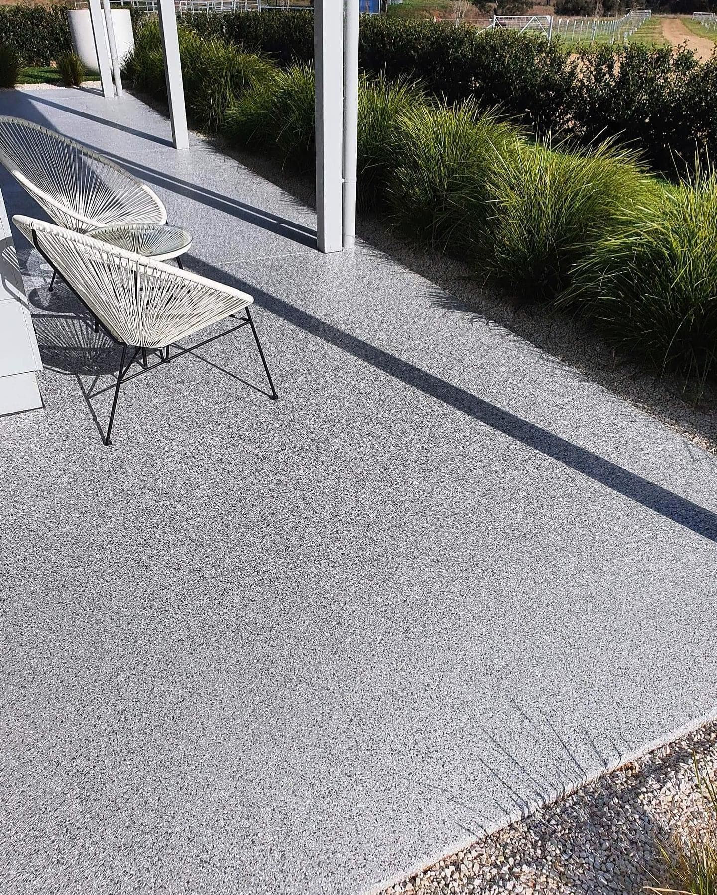 Patio with gray gravel, white chairs, and a long shadow, next to green bushes — Riverina Epoxy Flooring In Glenfield Park, NSW