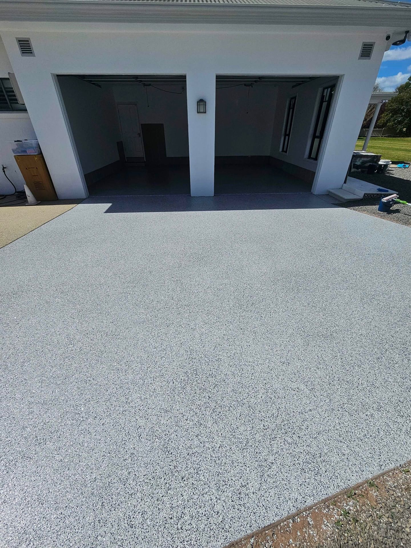 A light gray speckled epoxy driveway in front of a white two-car garage — Riverina Epoxy Flooring In Glenfield Park, NSW