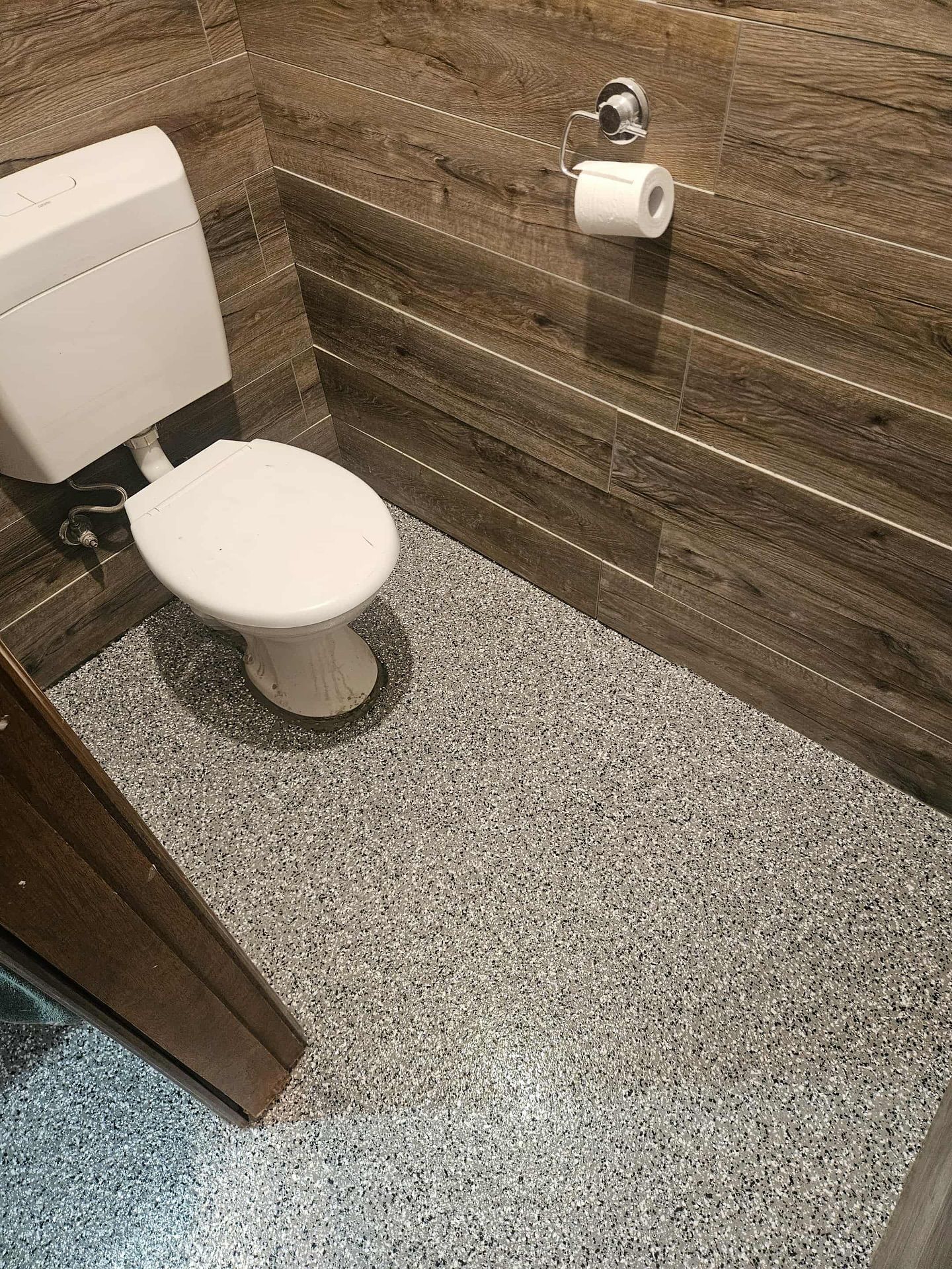 Small bathroom with white toilet, speckled gray floor, and brown tiled walls — Riverina Epoxy Flooring In Glenfield Park, NSW