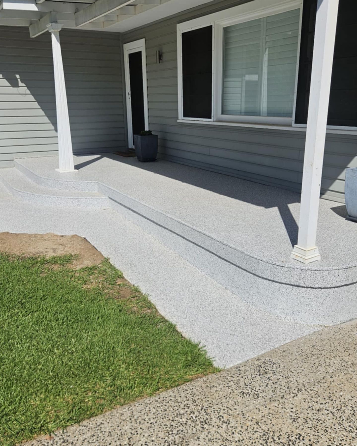 Exterior view of a gray house with a concrete ramp and steps leading to the entrance. Green grass on the left — Riverina Epoxy Flooring In Glenfield Park, NSW
