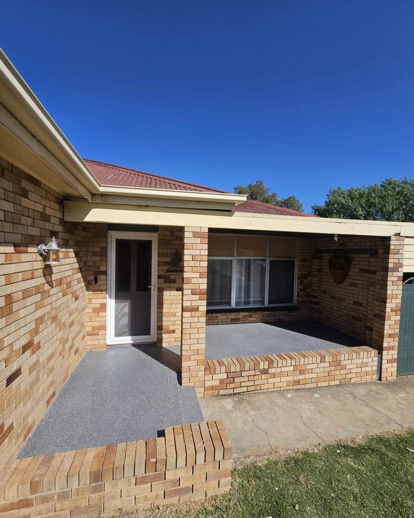 Brick house exterior with porch, blue sky — Riverina Epoxy Flooring In Glenfield Park, NSW