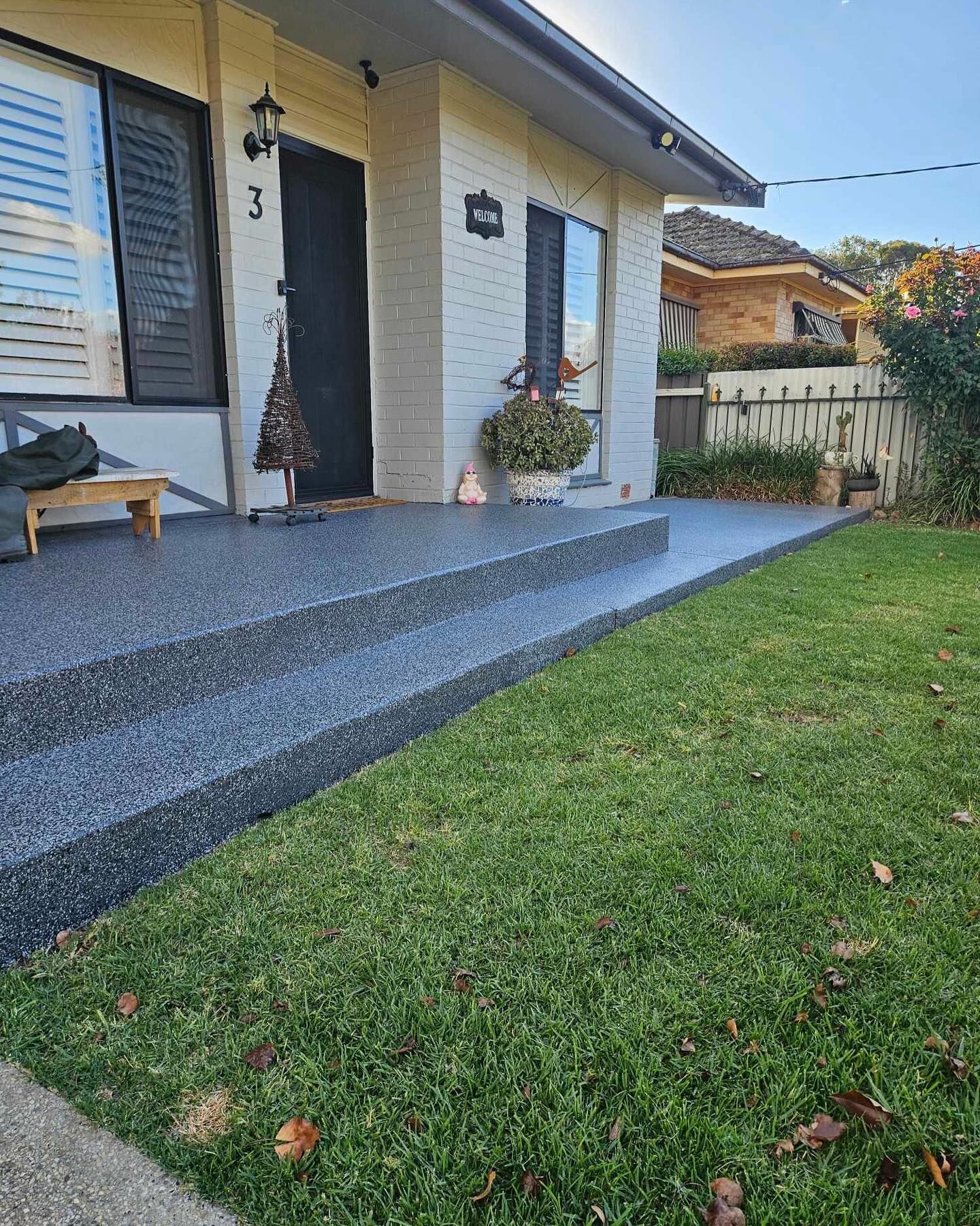 House front with textured gray concrete steps, lawn, and pale brick exterior — Riverina Epoxy Flooring In Glenfield Park, NSW