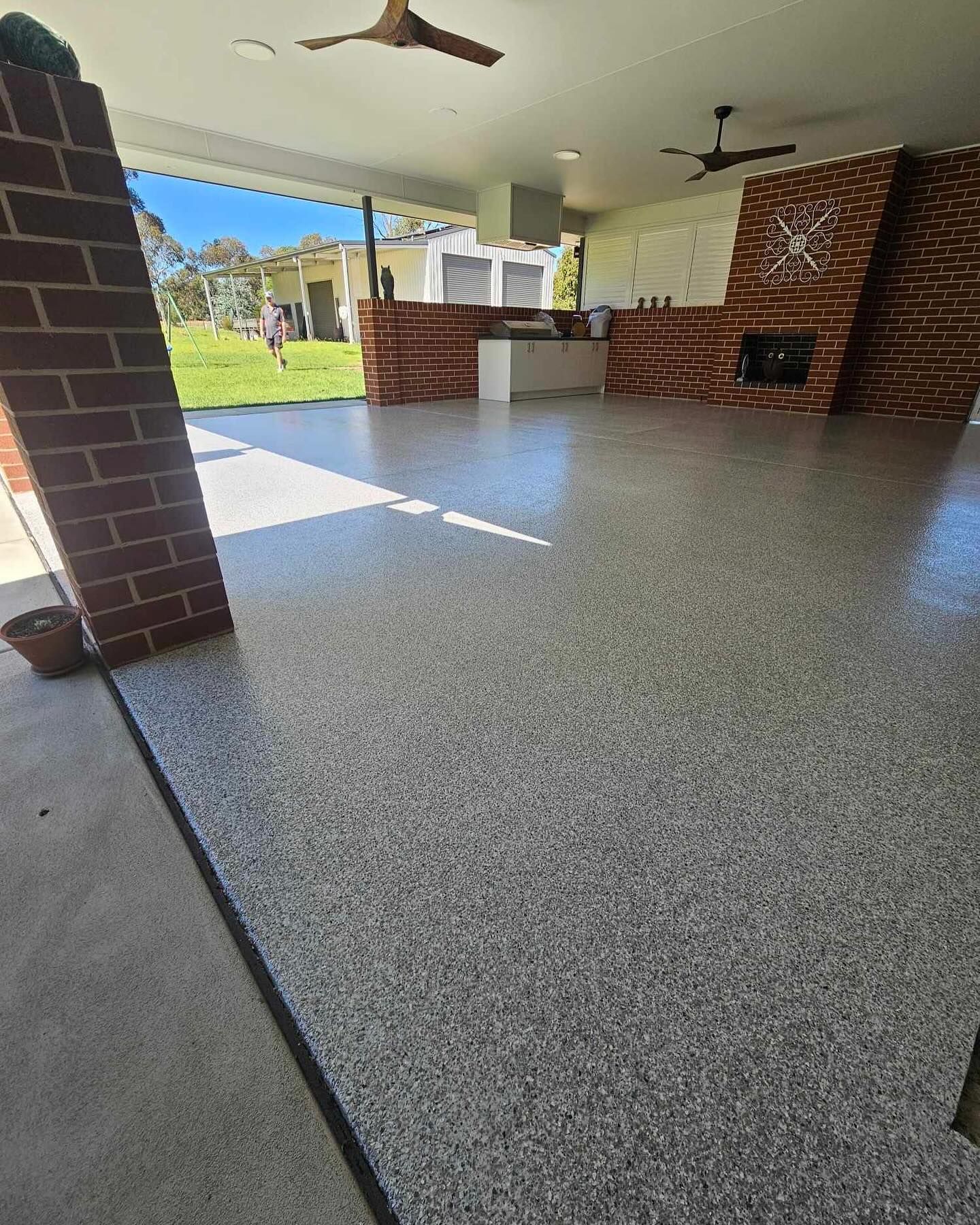 Patio with speckled gray flooring, brick accents, and outdoor kitchen — Riverina Epoxy Flooring In Glenfield Park, NSW