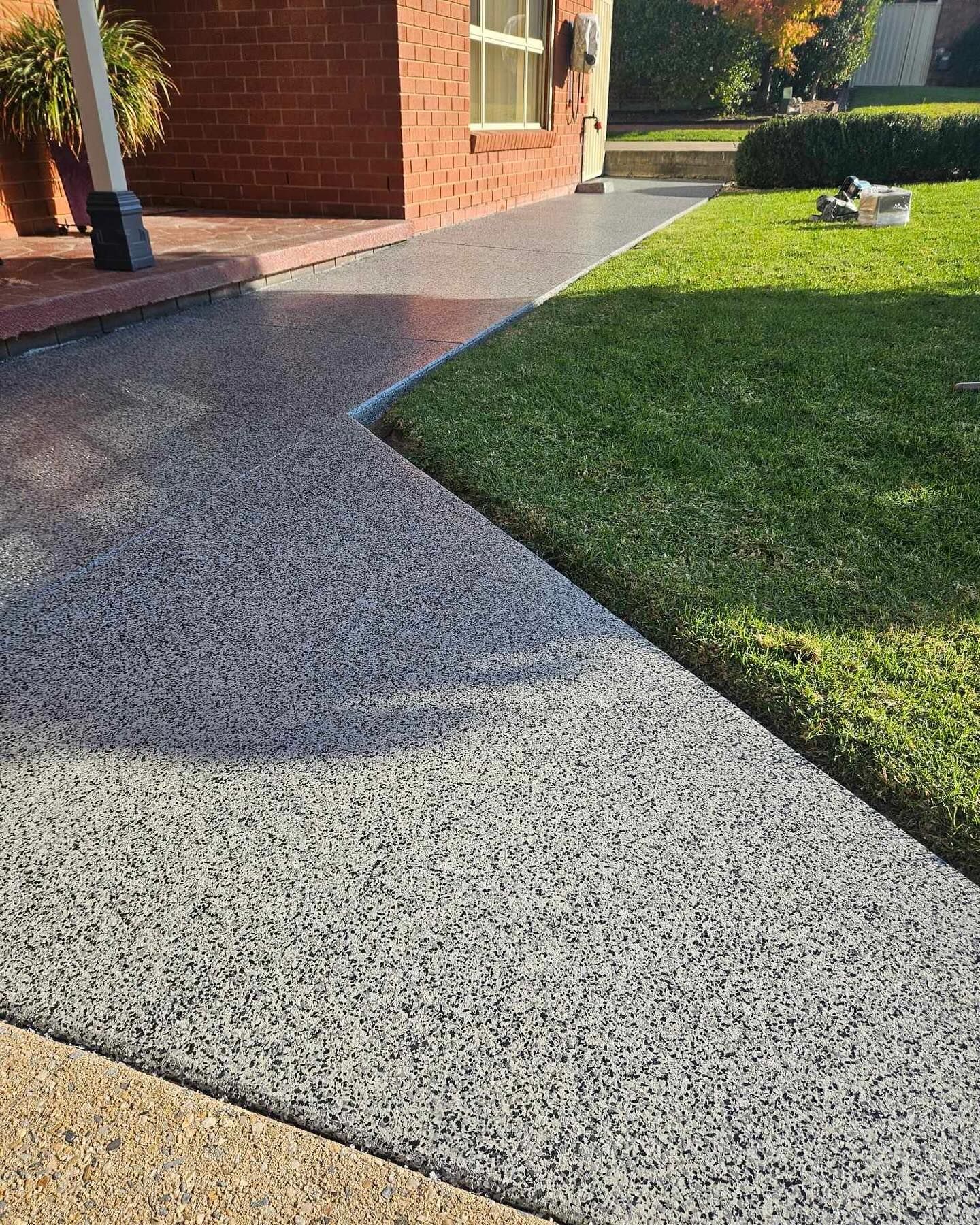 Driveway and walkway with aggregate surface, bordered by green grass and a brick house — Riverina Epoxy Flooring In Glenfield Park, NSW