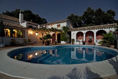 a large swimming pool in front of a house at night