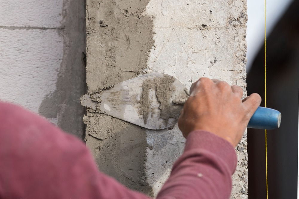 a person is using a trowel to spread cement on a wall