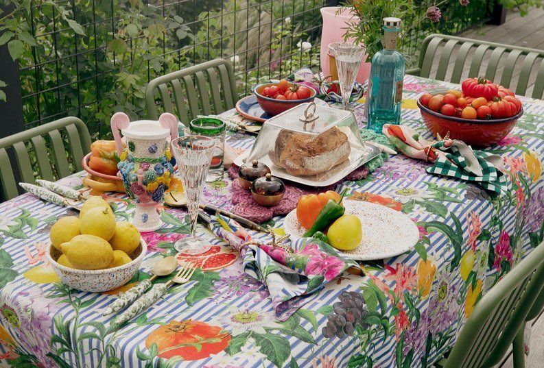 A table with a floral tablecloth and plates of food on it.